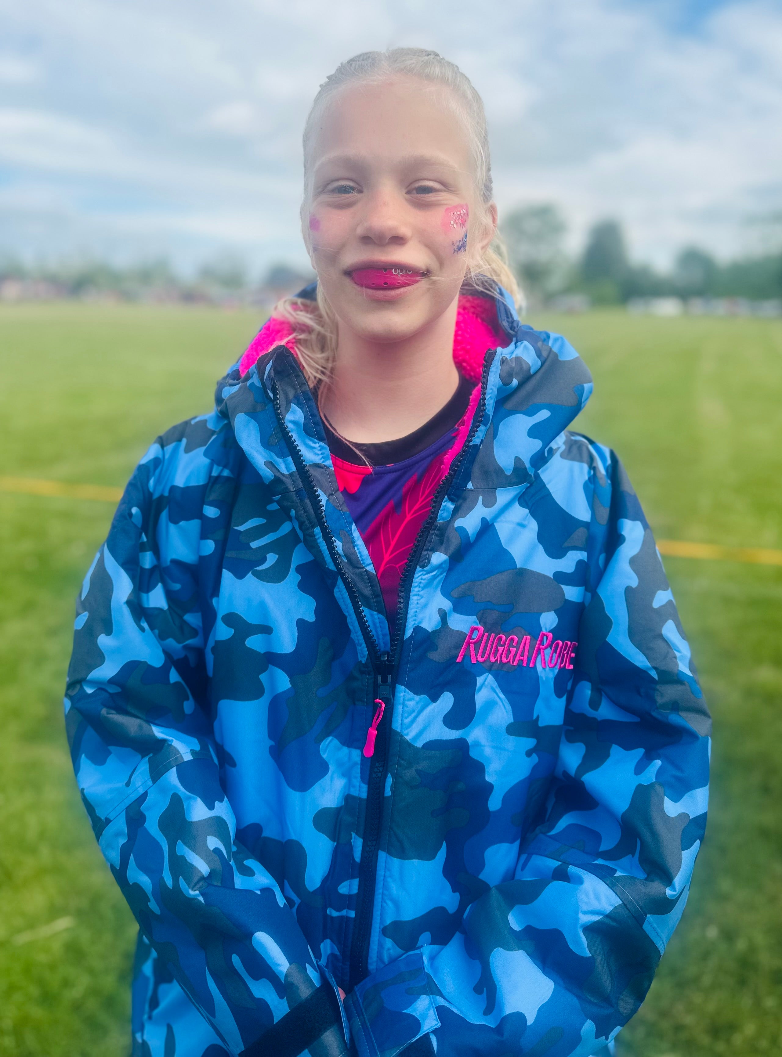 Person wearing a blue camouflage ruggarobe with pink interior on a grassy field