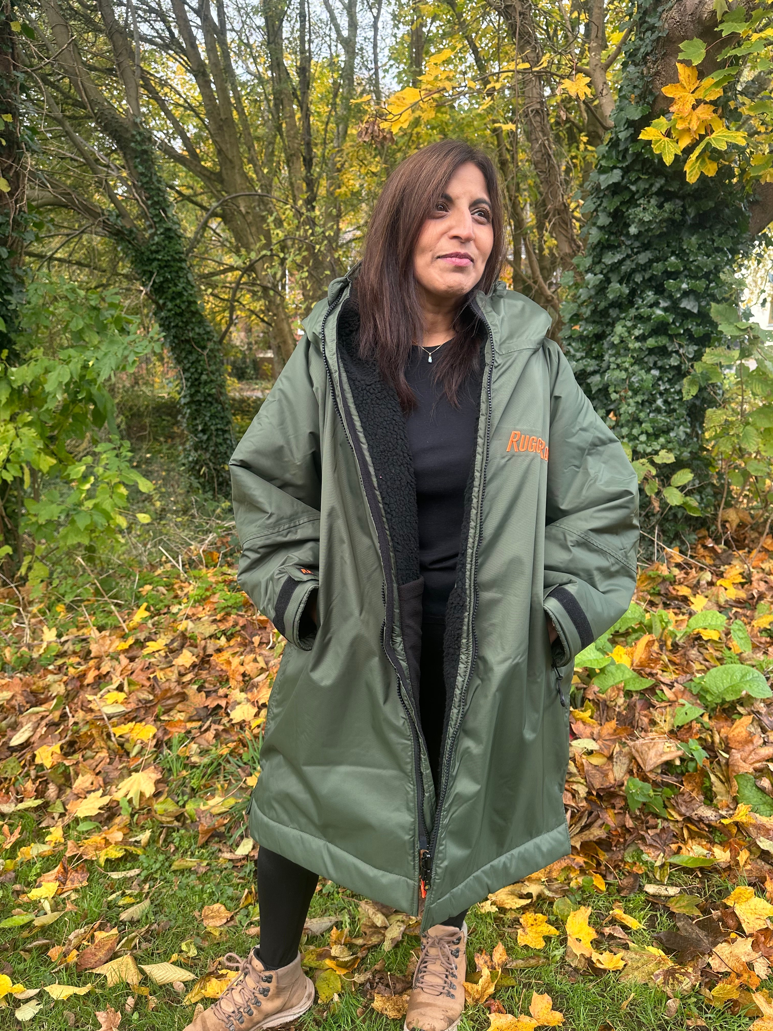 Woman wearing a green change robe with black fleece with a brand logo in a field