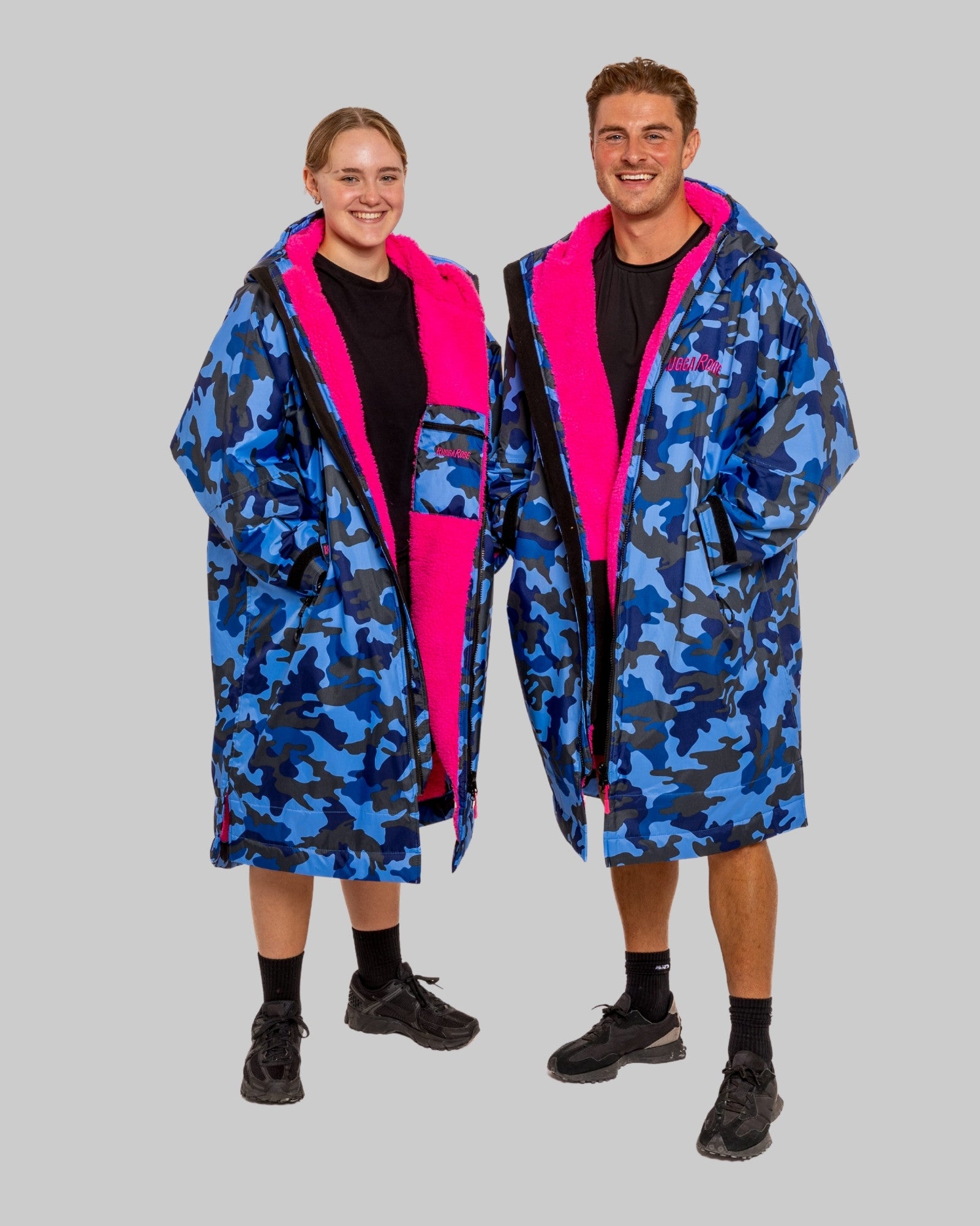 Two people wearing blue camouflage ruddarobes with hoods on a gray background