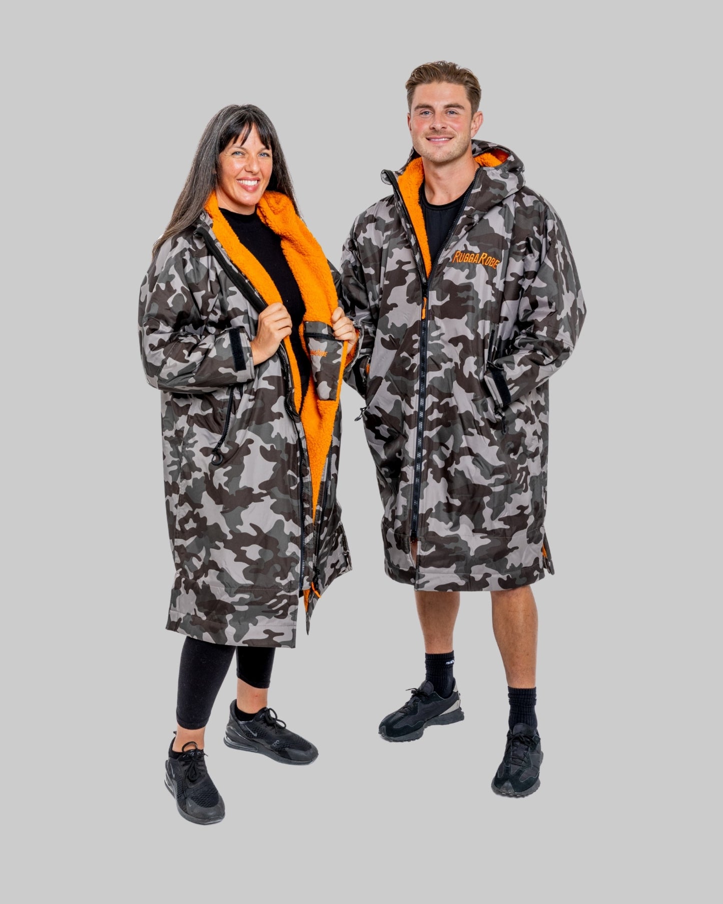 Two models wearing RuggaRobe grey camo change robe with orange fleece interior on grey background