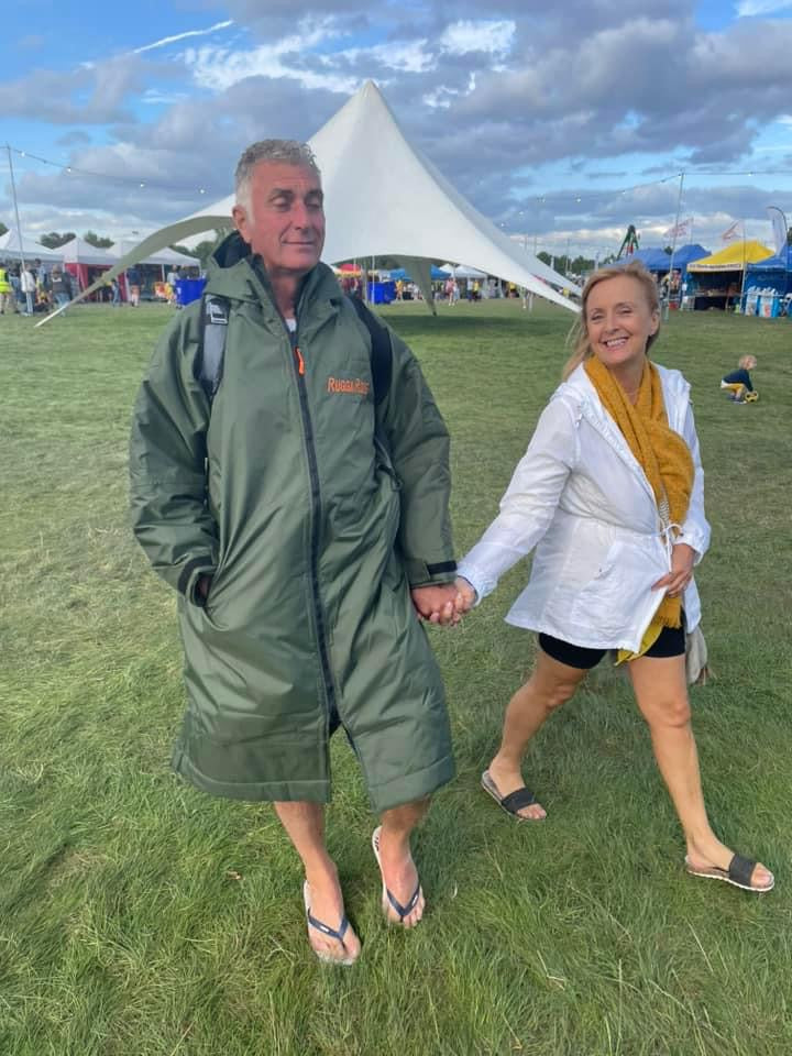 Two people holding hands on a grassy field with tents in the background