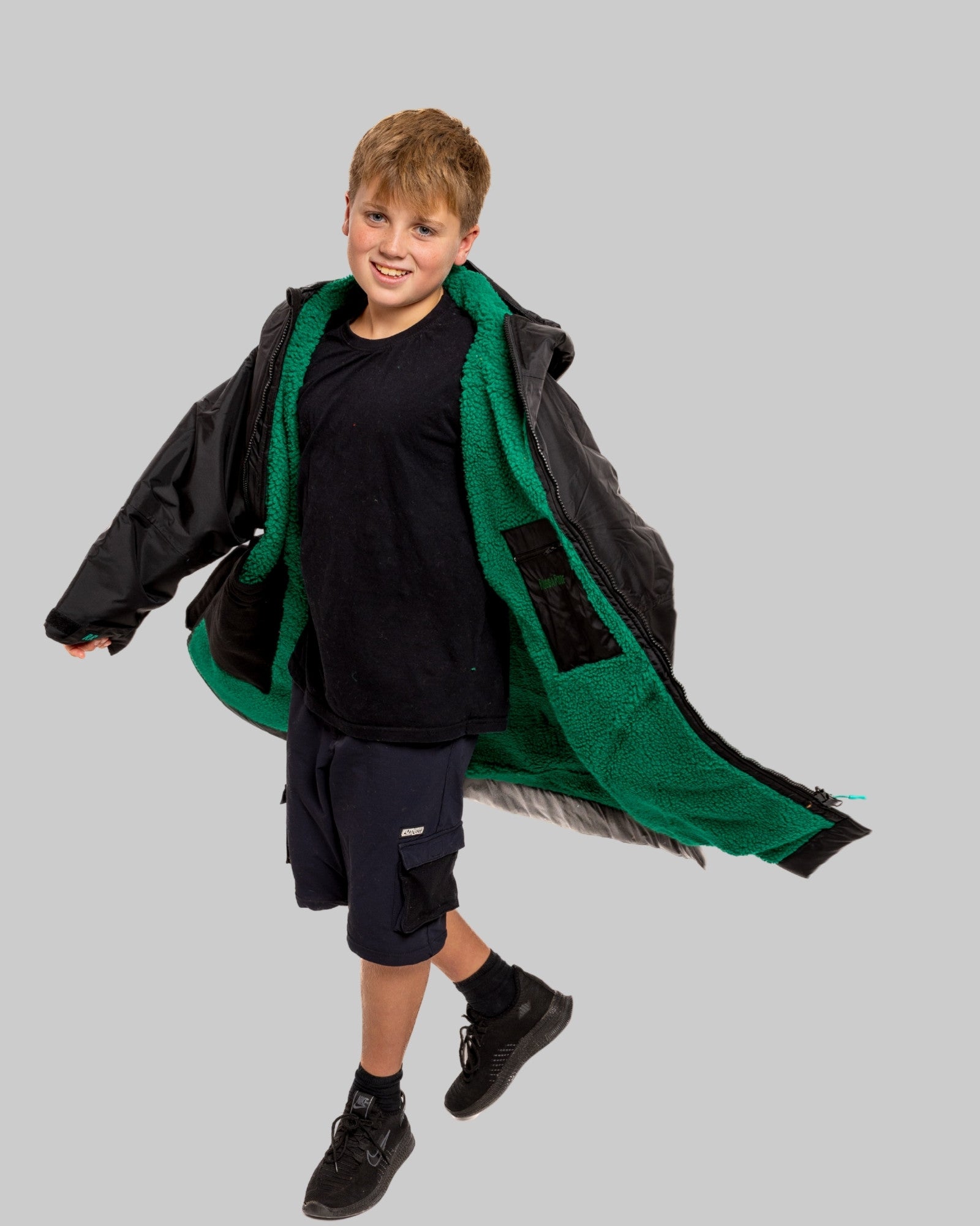 Model wearing RuggaRobe black change robe with green fleece interior on grey background