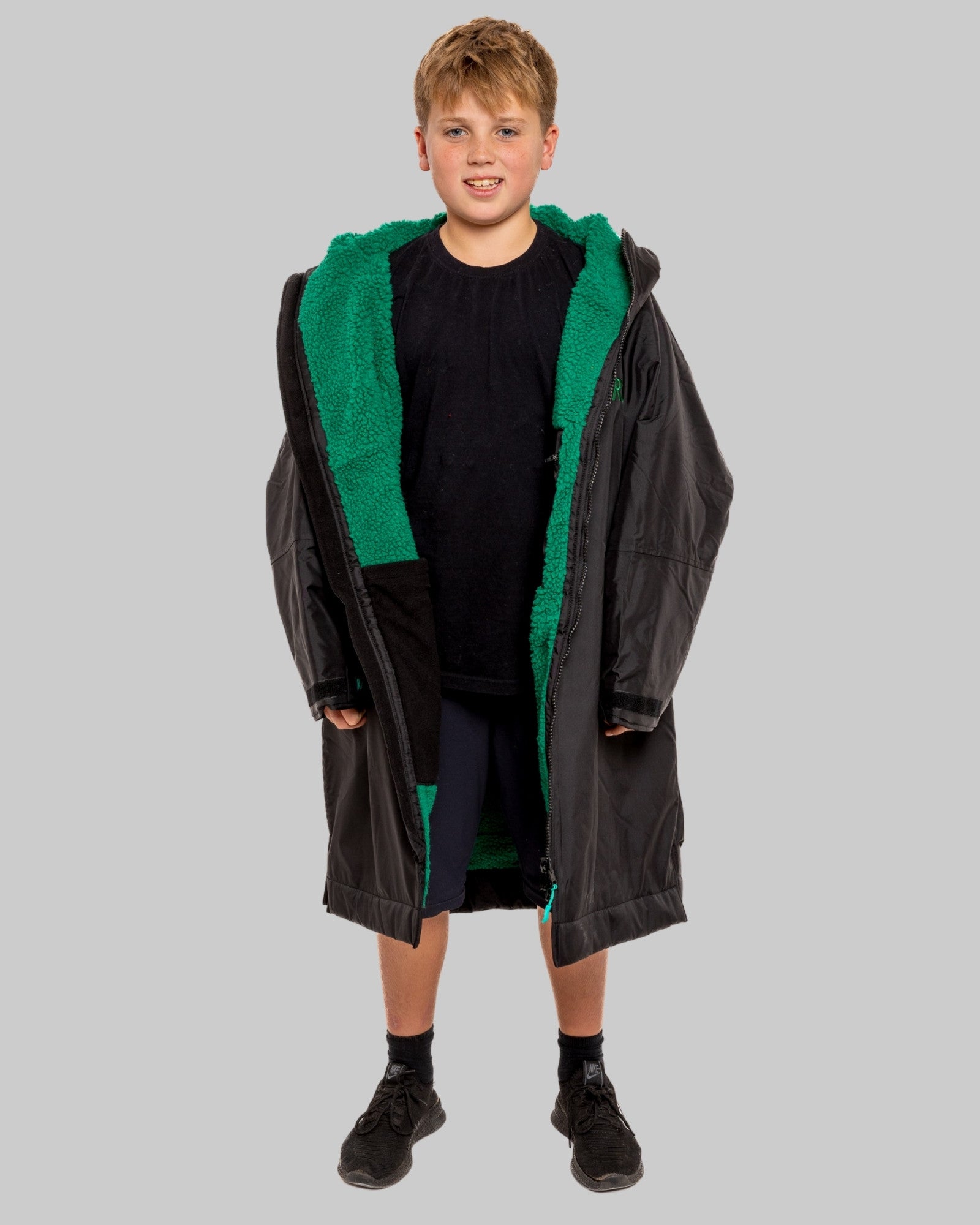 Model wearing RuggaRobe black change robe with green fleece interior on grey background