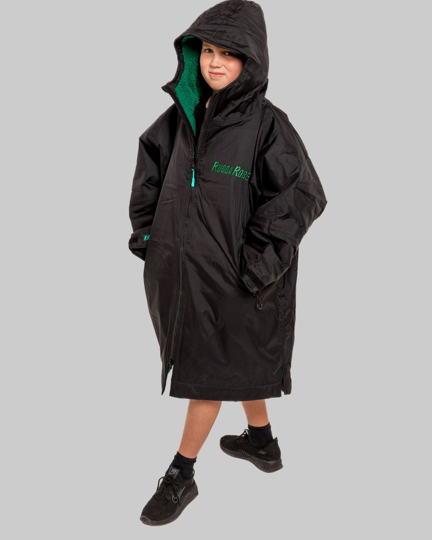 Model wearing RuggaRobe black change robe with green fleece interior on grey background