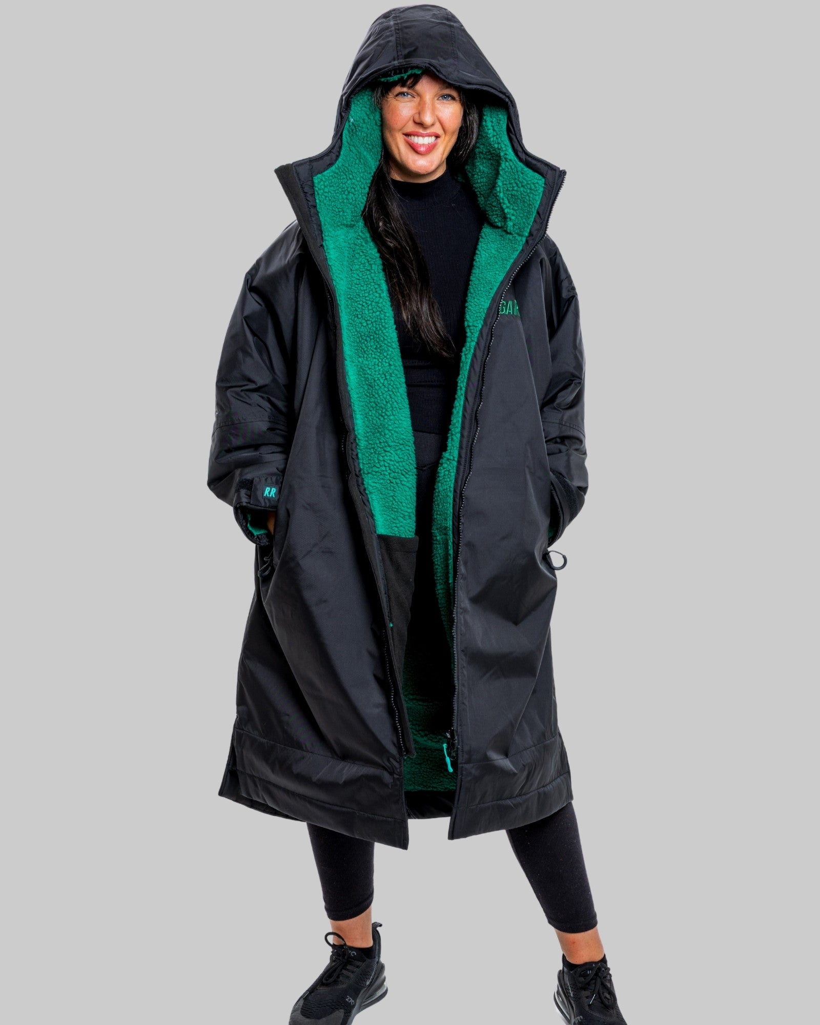 Person wearing a black changerobe with green lining on a gray background