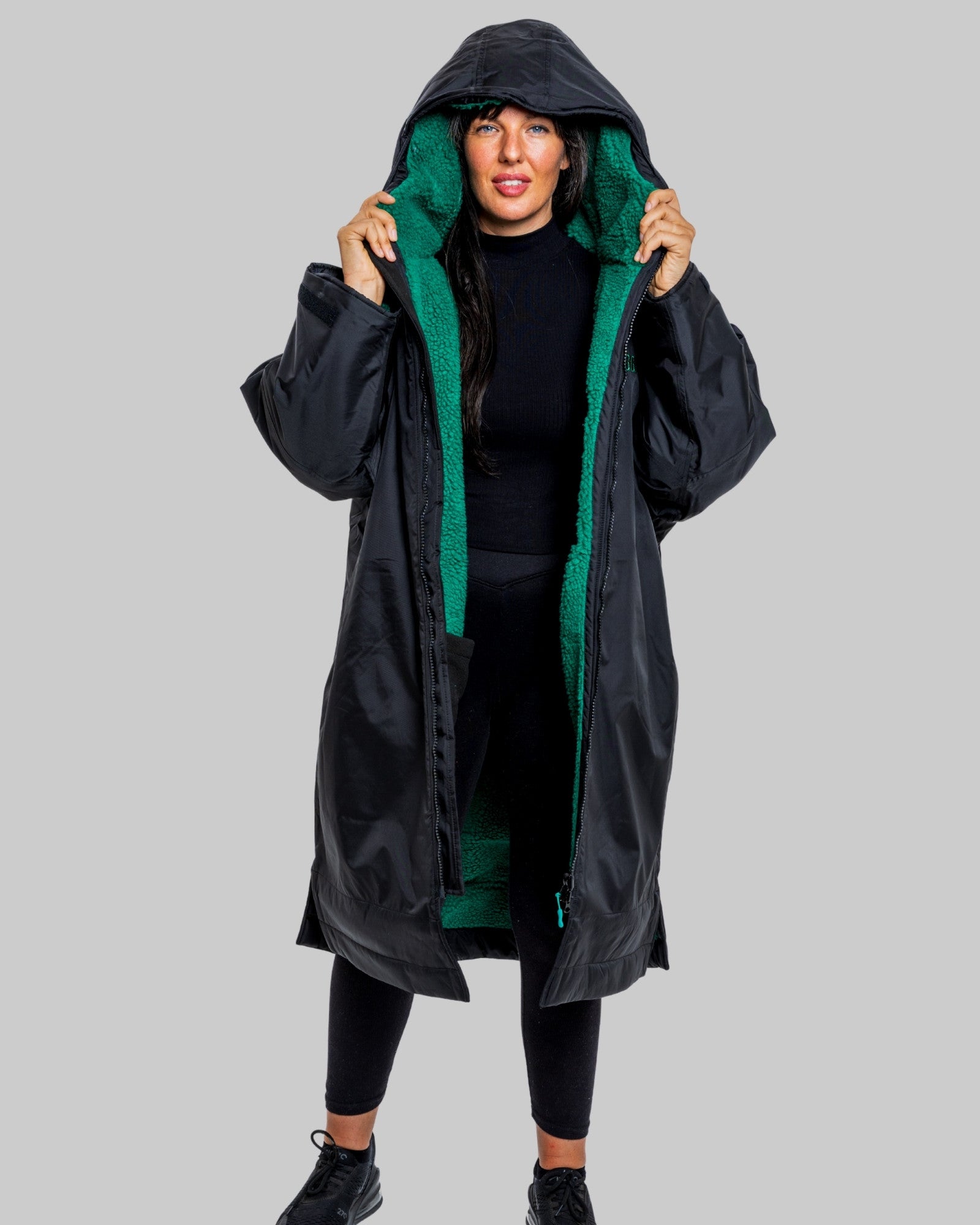 Person wearing a black changerobe with green lining on a gray background
