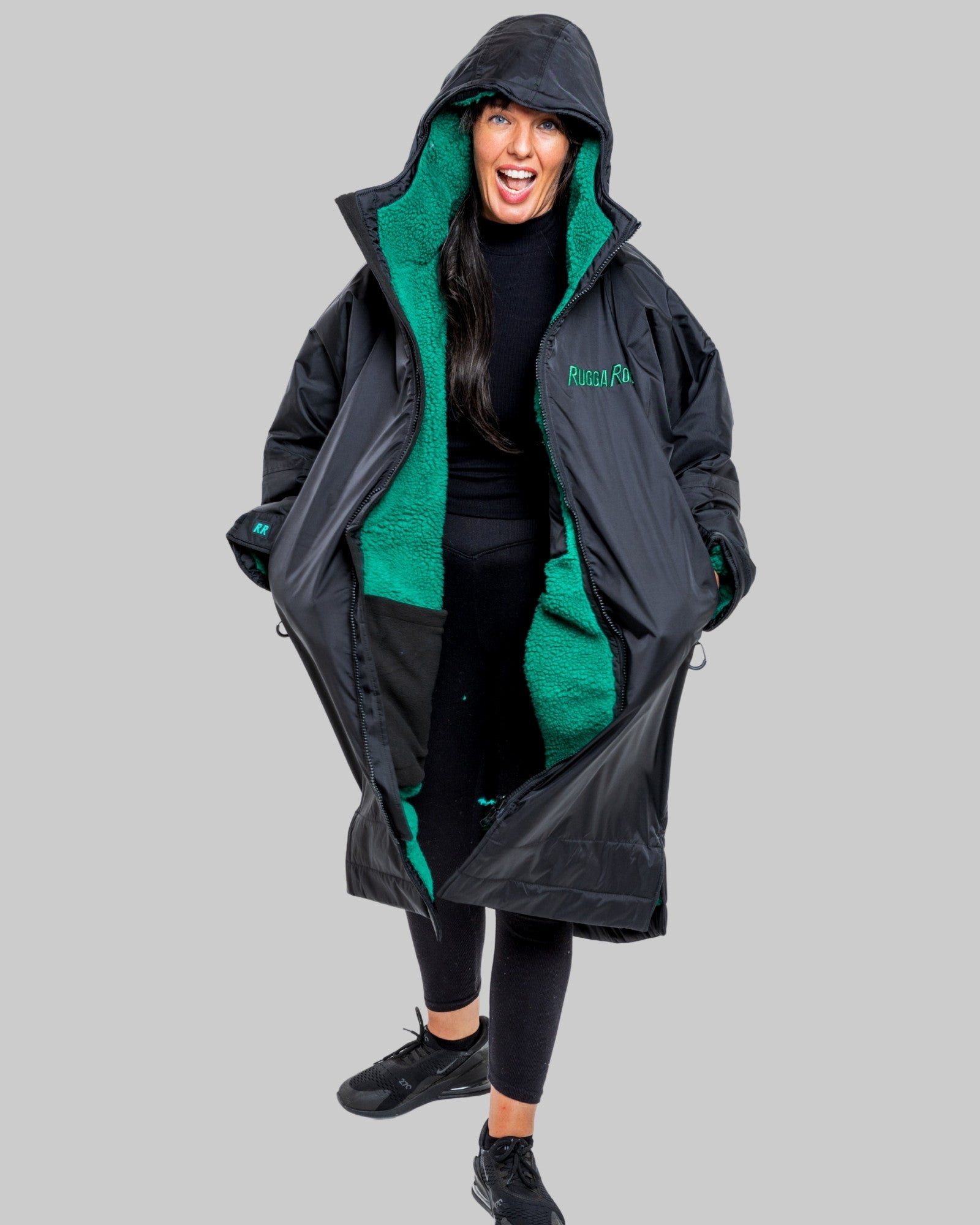 Person wearing a black changerobe with green lining on a gray background