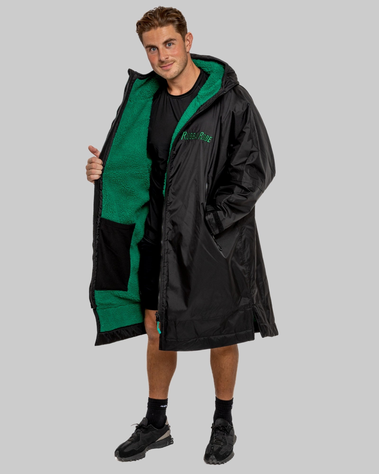 Person wearing a black changerobe with green lining on a gray background