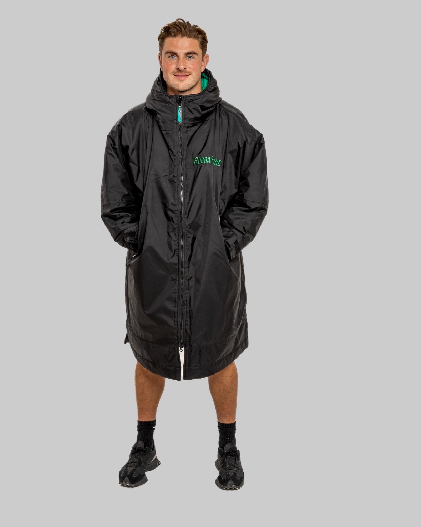 Person wearing a black changerobe with green lining on a gray background