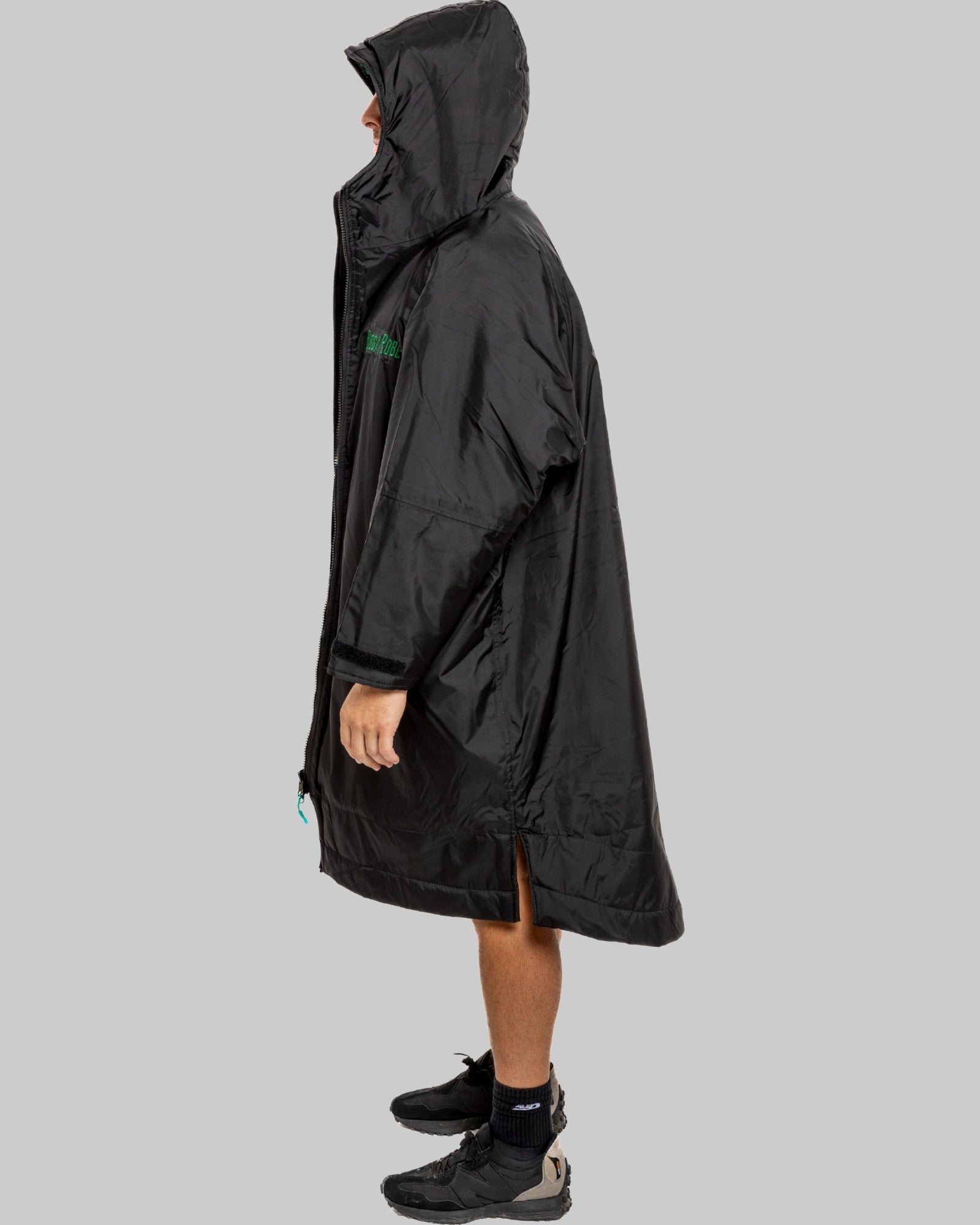 Person wearing a black changerobe with green lining on a gray background