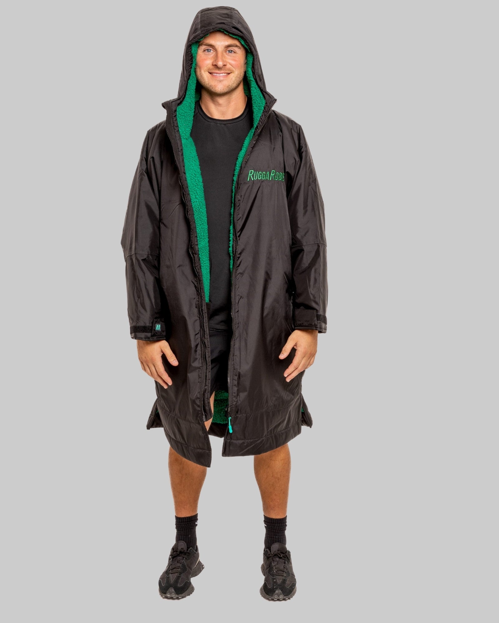 Person wearing a black changerobe with green lining on a gray background