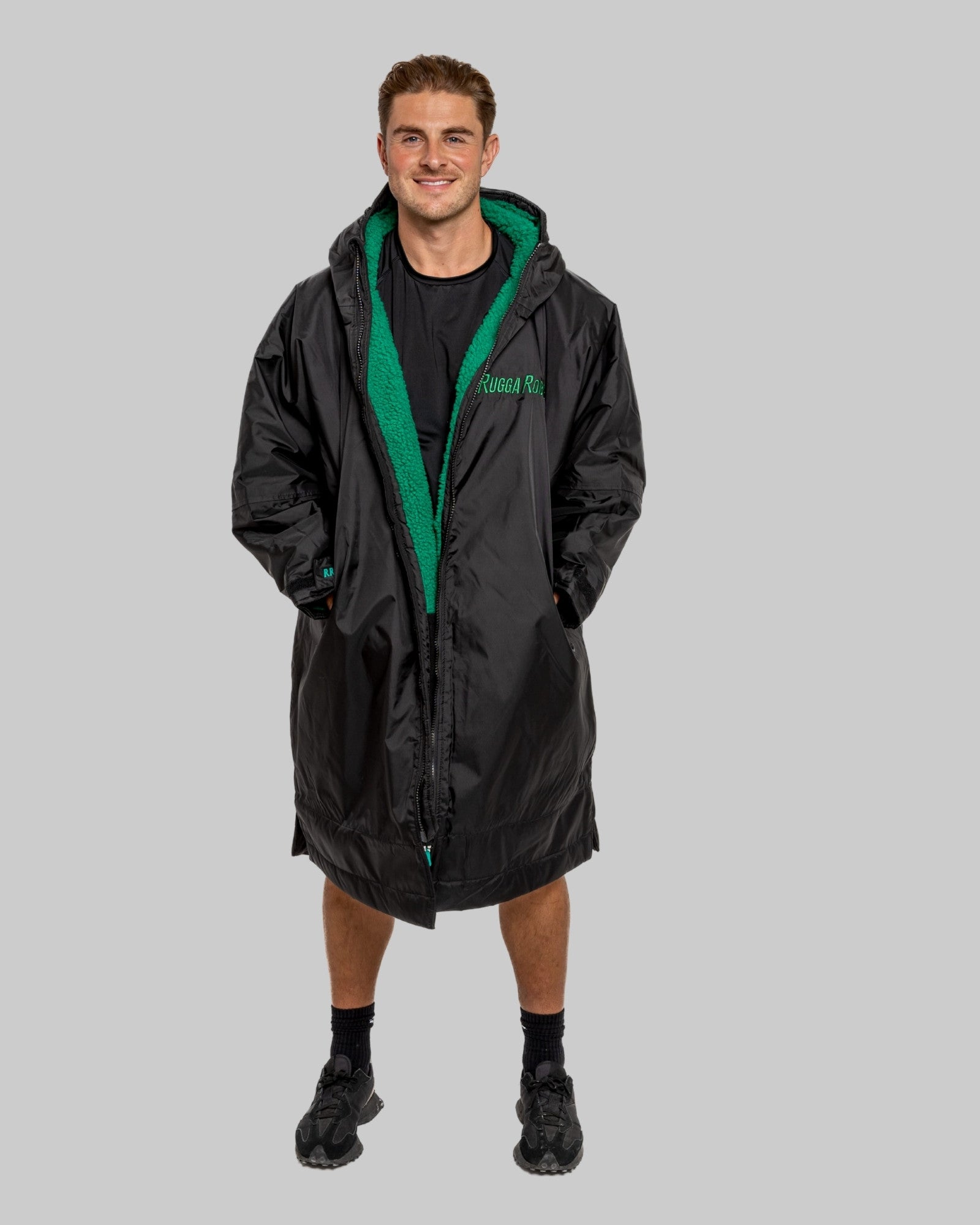 Person wearing a black changerobe with green lining on a gray background