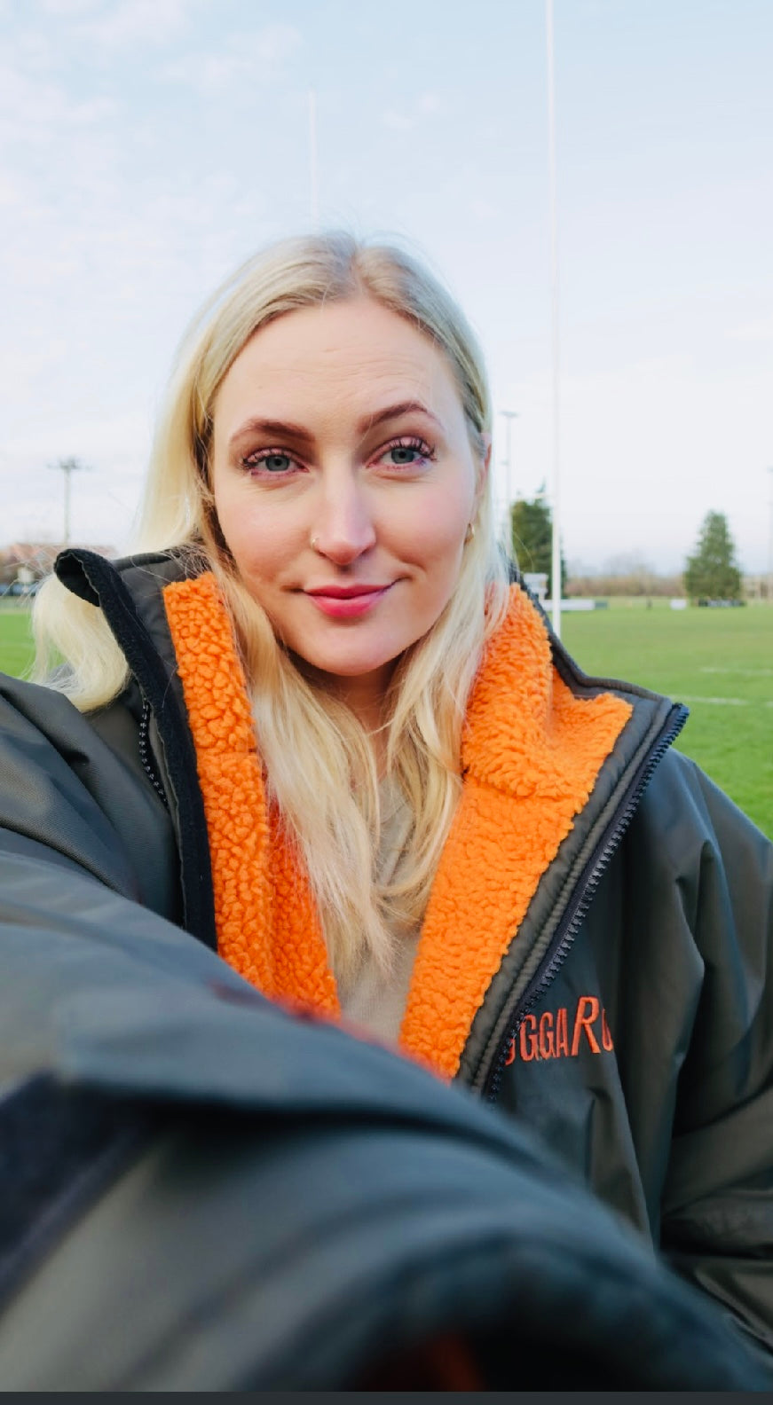 Person wearing a black ruggarobe with orange interior in an outdoor setting