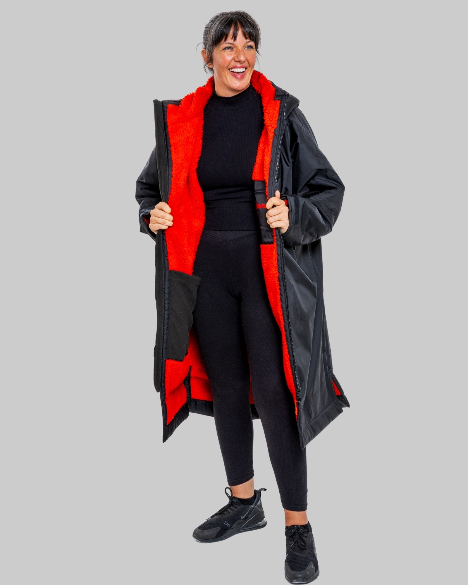 Person wearing a black change robe with red fleece on a grey background
