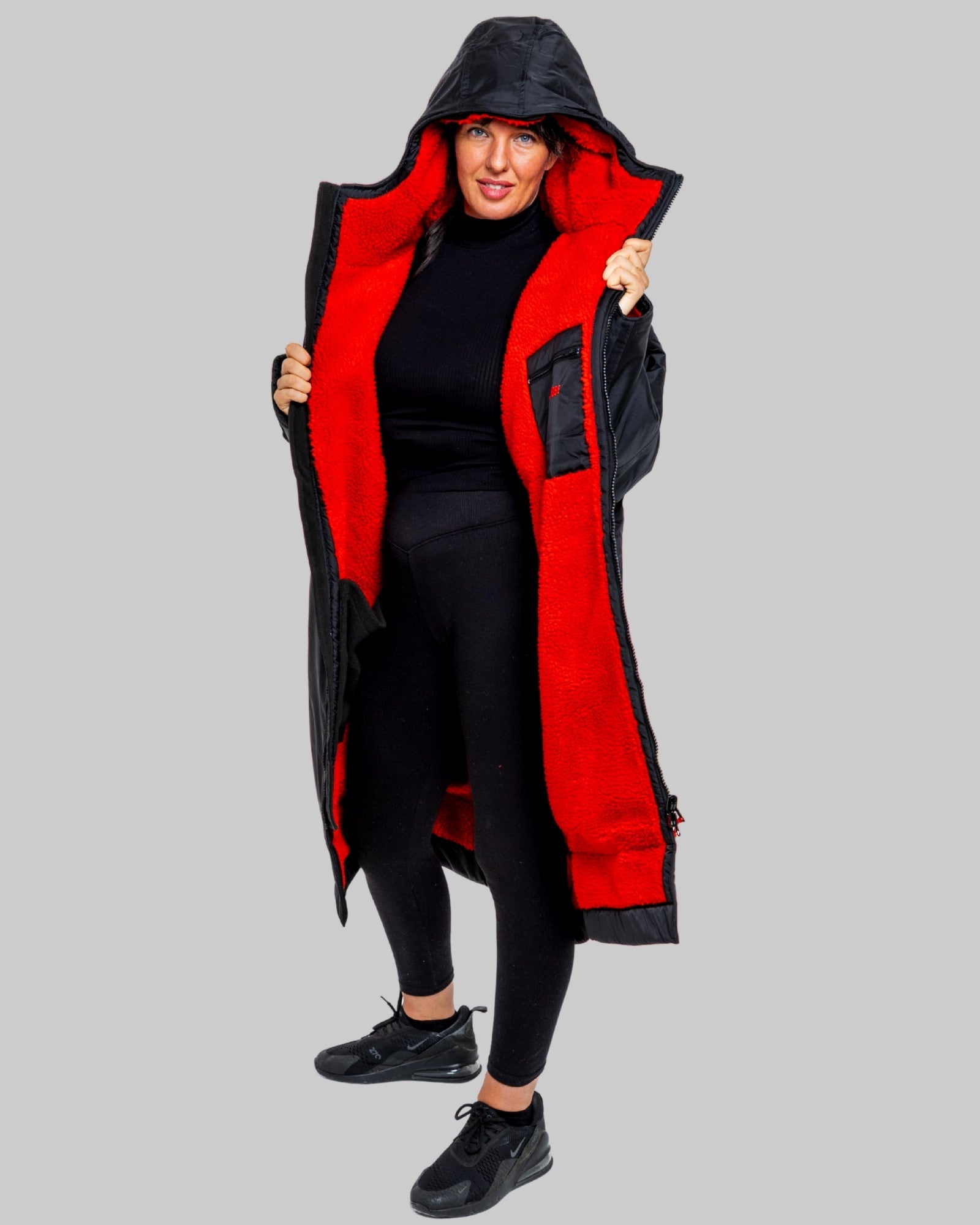 Person wearing a black and red hooded changerobe on a gray background