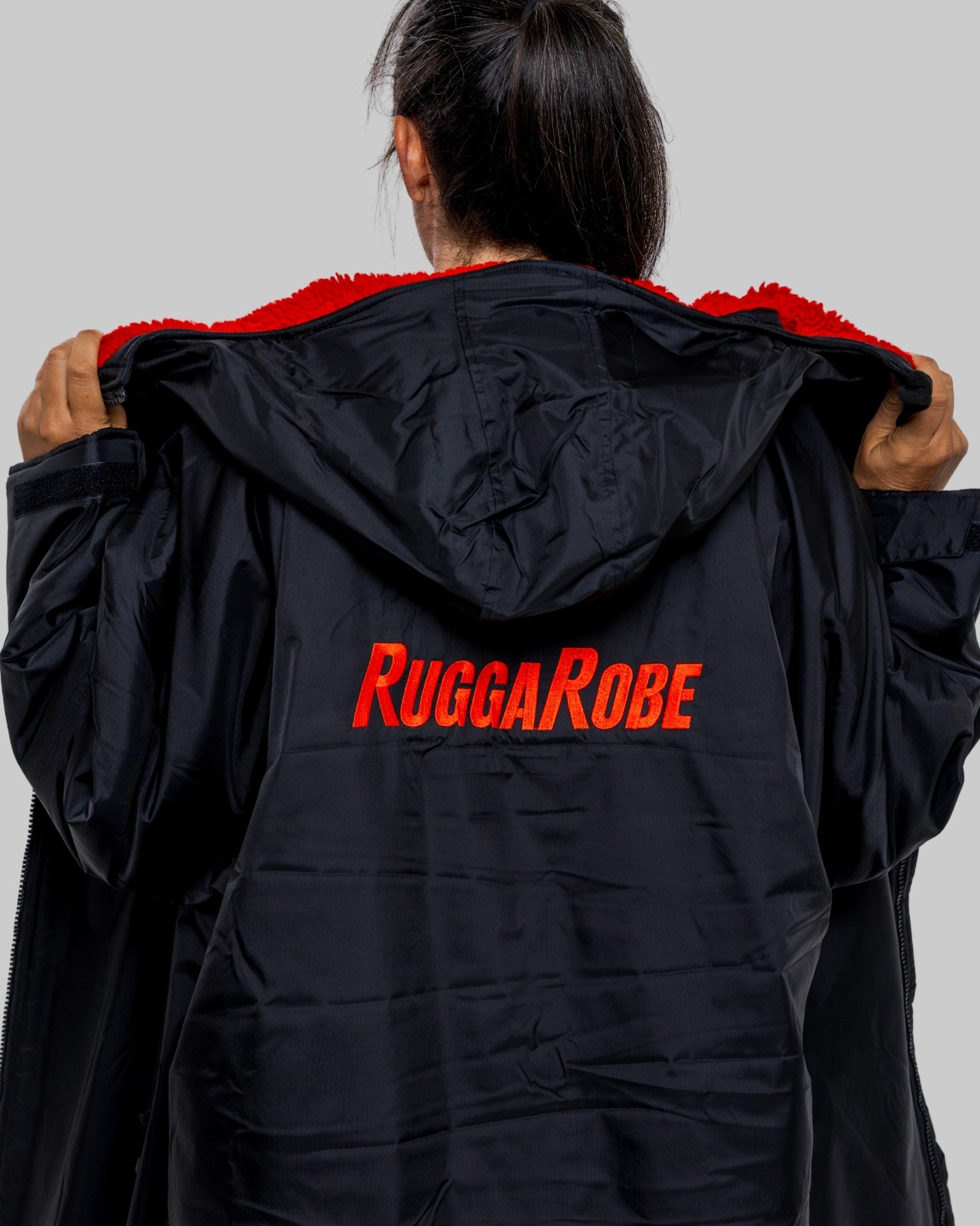 Person wearing a black changerobe with 'RuggaRobe' logo on the back against a gray background