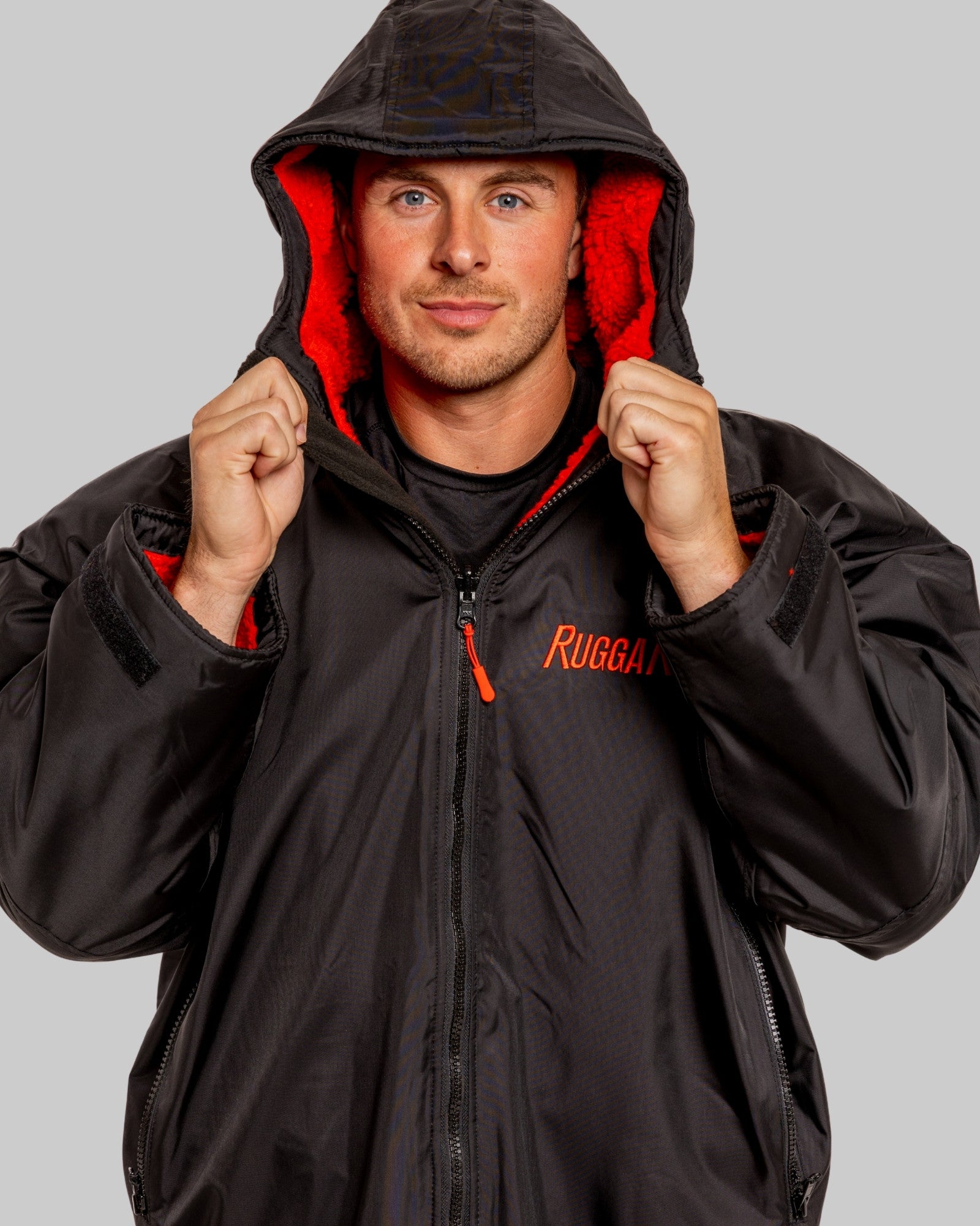 Man wearing a black ruggarobe jacket with red interior and 'Ruggrobe' branding on a gray background