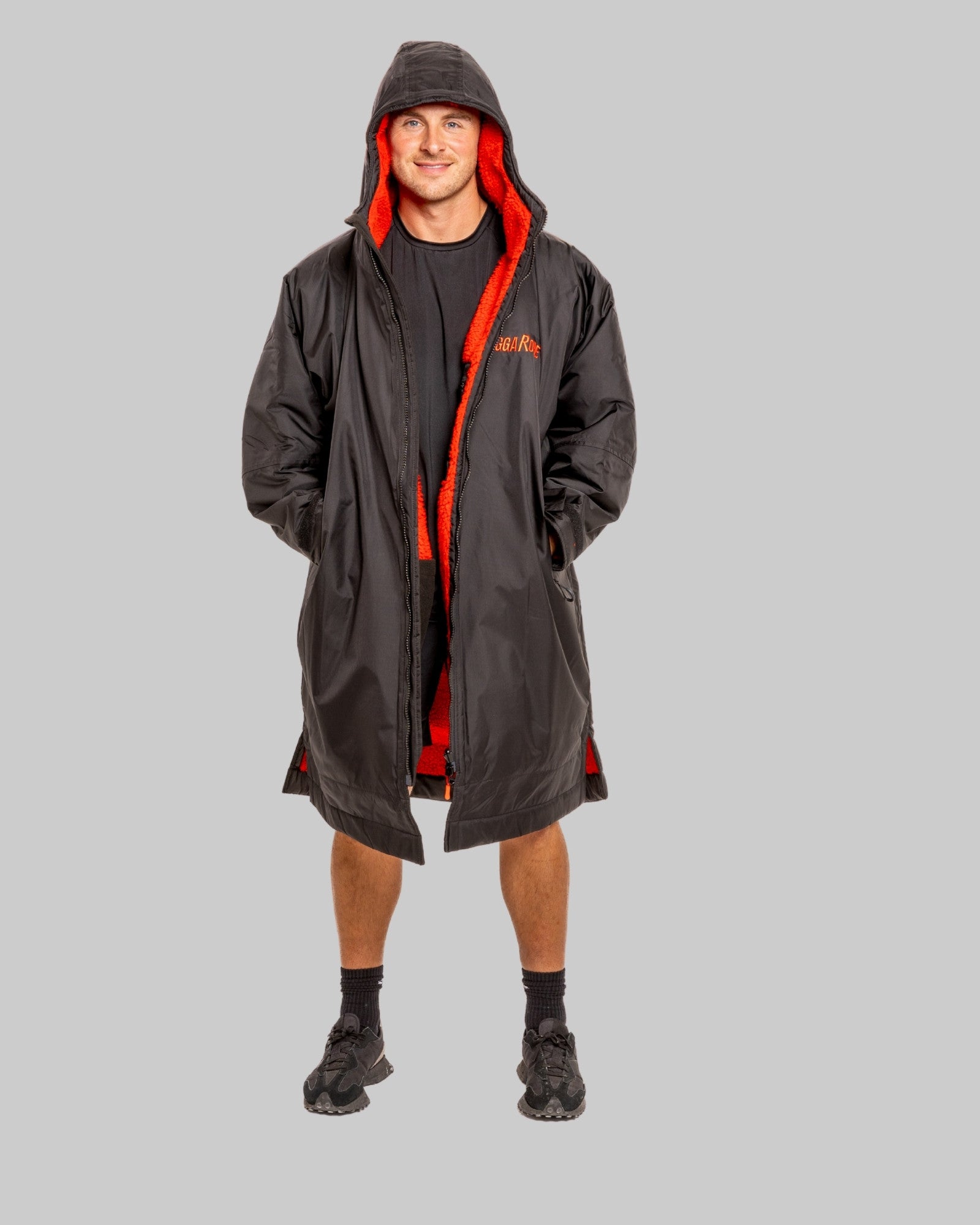 Person wearing a black change robe with red fleece on a grey background