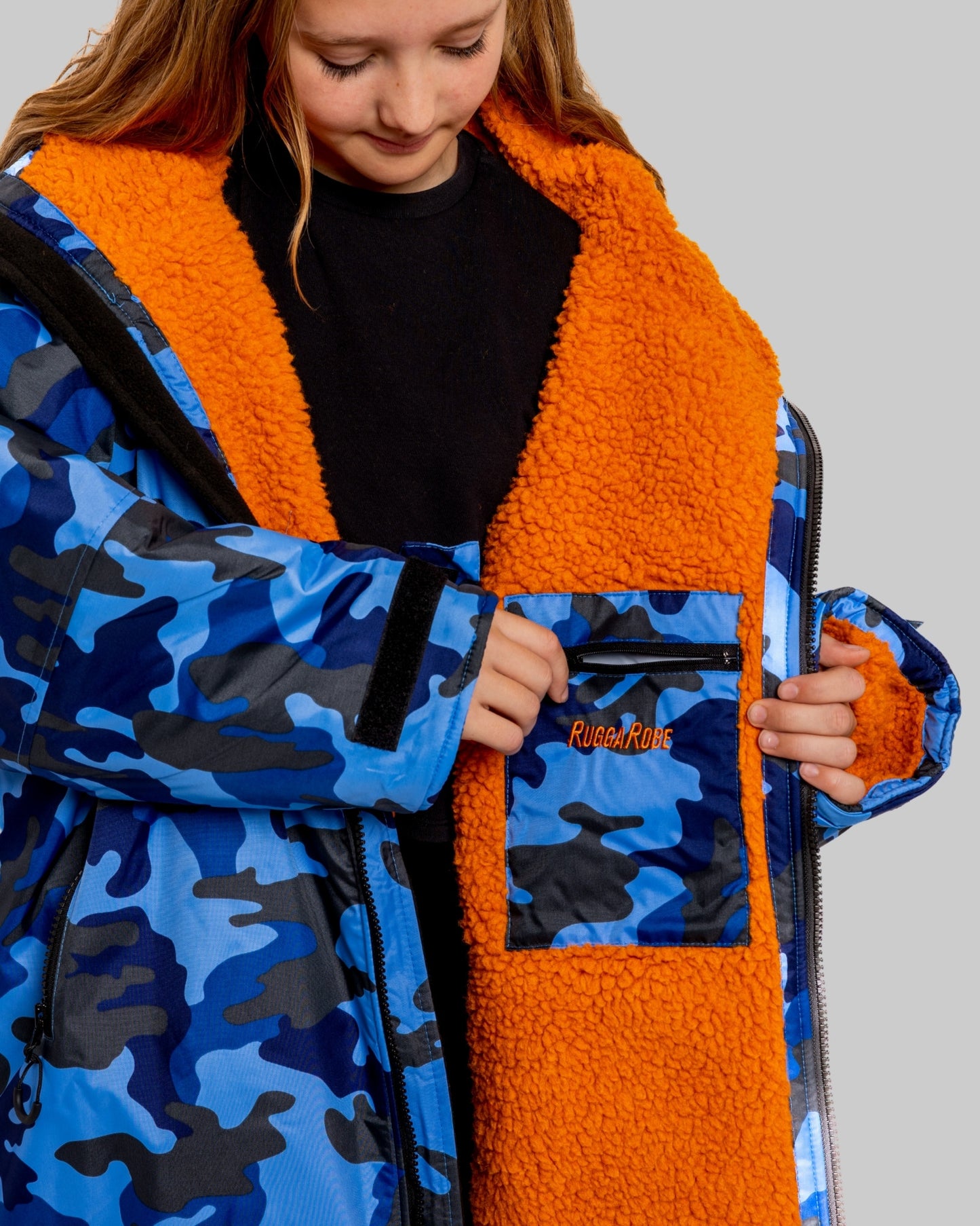 Child wearing a blue camouflage and orange ruggarobe with a visible brand logo.