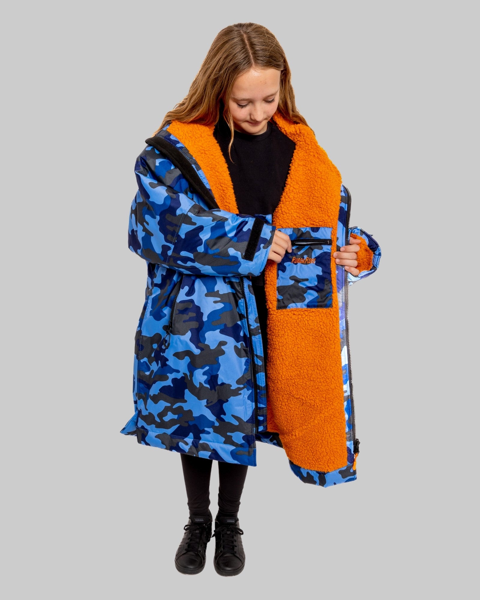 Model wearing RuggaRobe blue camo change robe with orange fleece interior on grey background