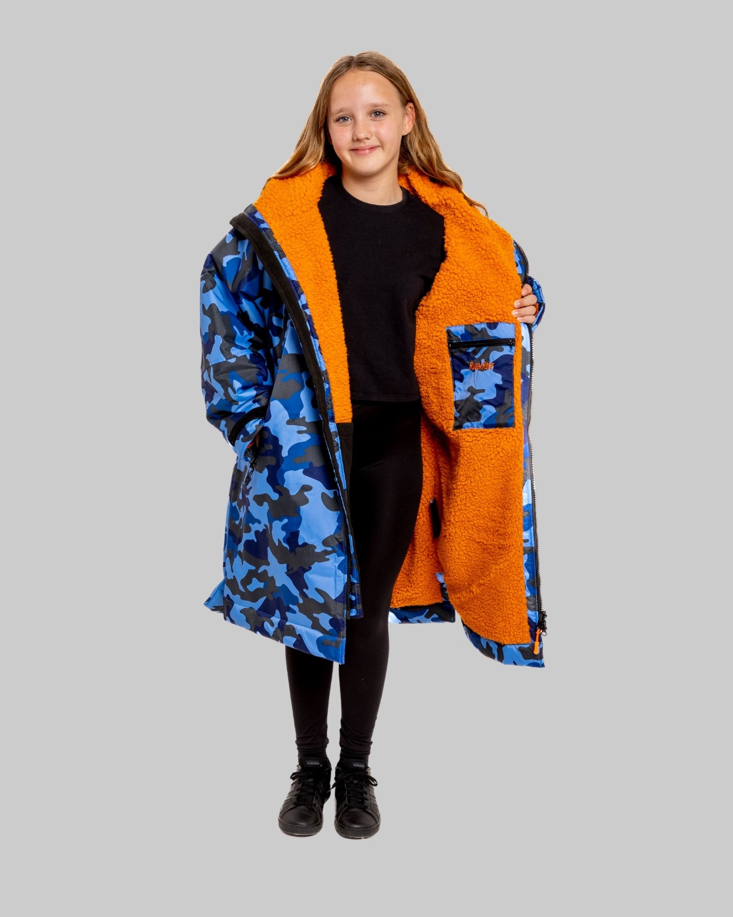 Model wearing RuggaRobe blue camo change robe with orange fleece interior on grey background