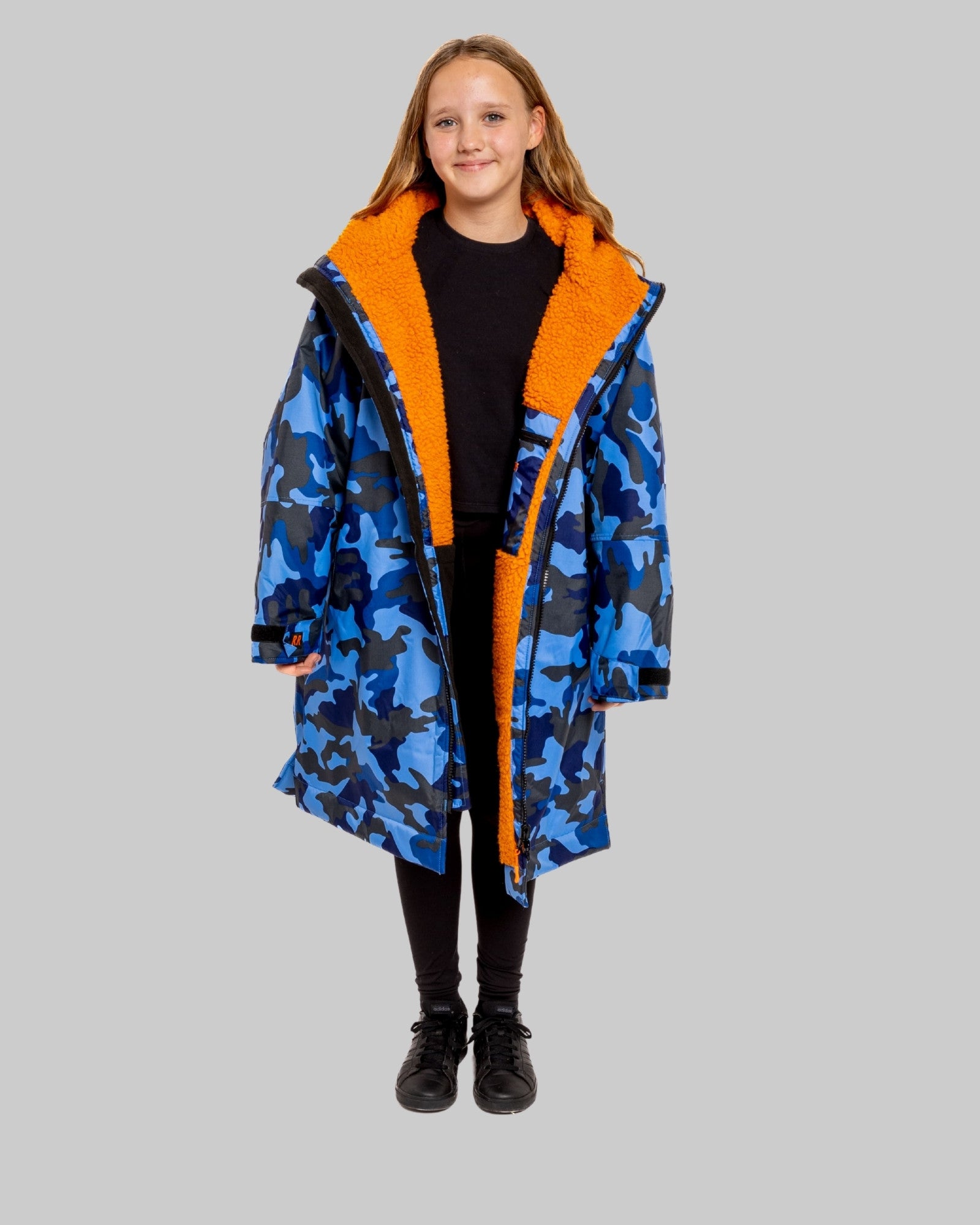 Model wearing RuggaRobe blue camo change robe with orange fleece interior on grey background