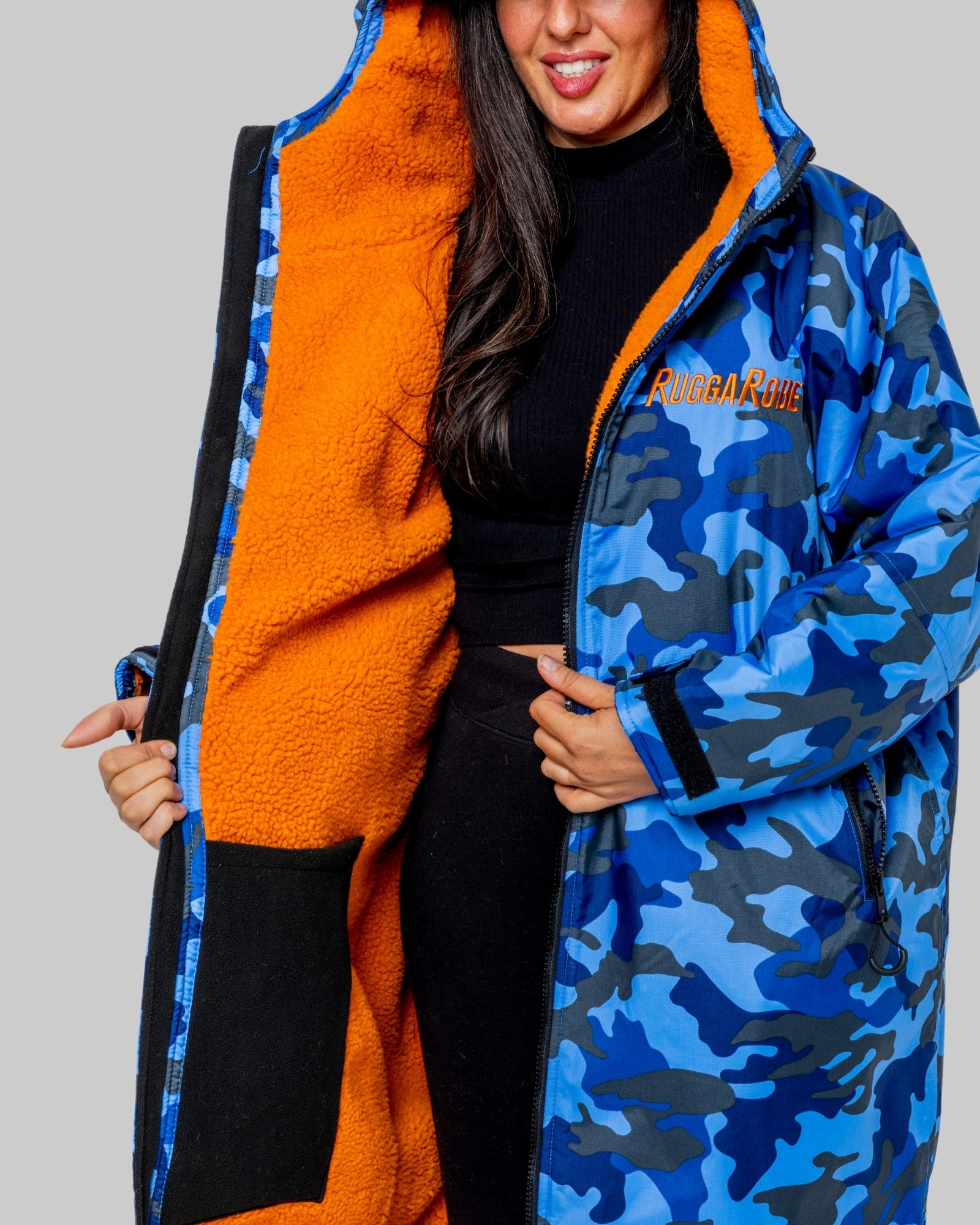 Person wearing a blue camouflage ruggarobe with orange lining on a gray background