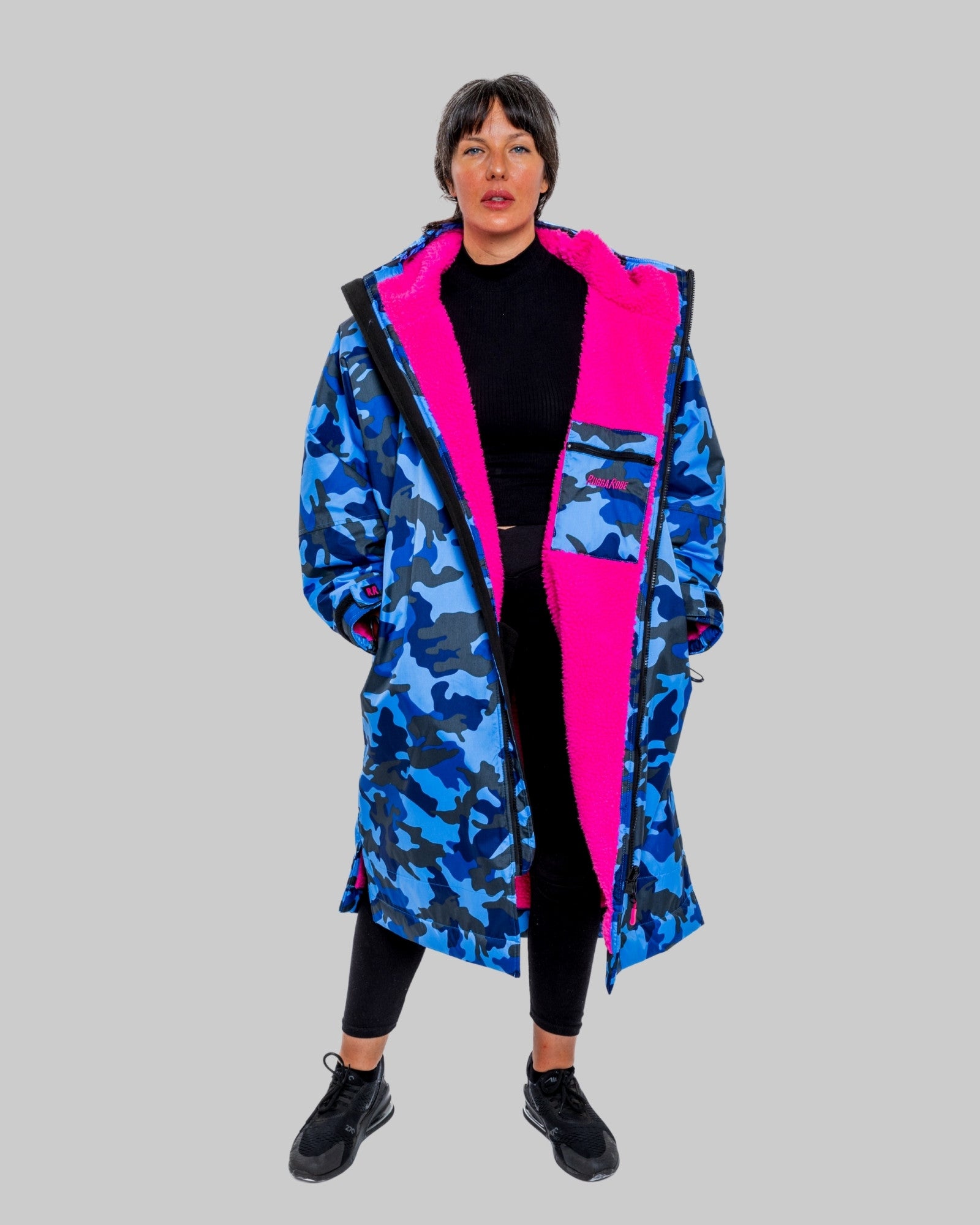 Person wearing a blue camouflage ruggarobe with pink accents on a gray background