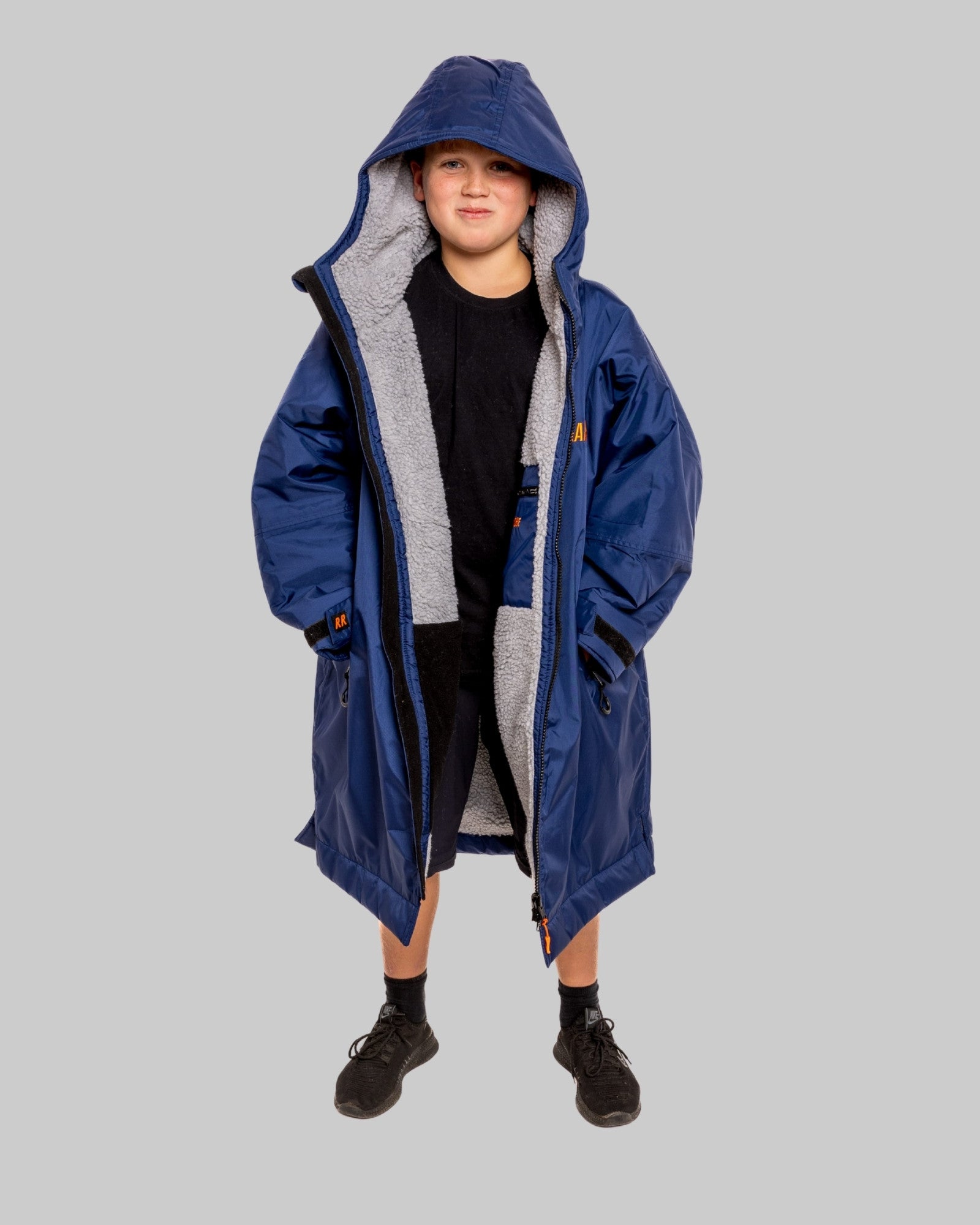 Child wearing a blue RuggaRobe with grey fleece interior change robe on a grey background