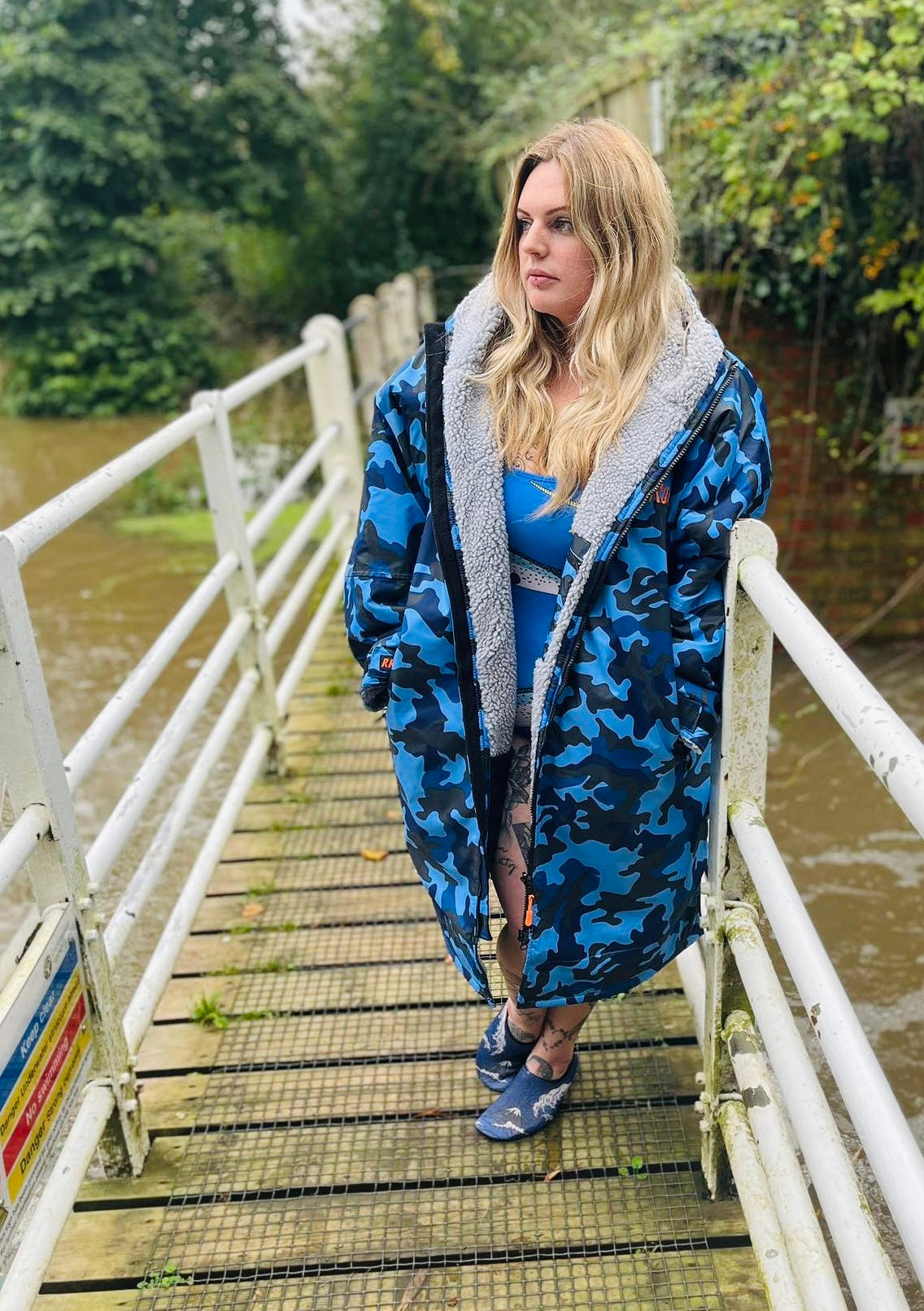 Woman wearing a blue ruggarobe camouflage changerobe on a wooden bridge