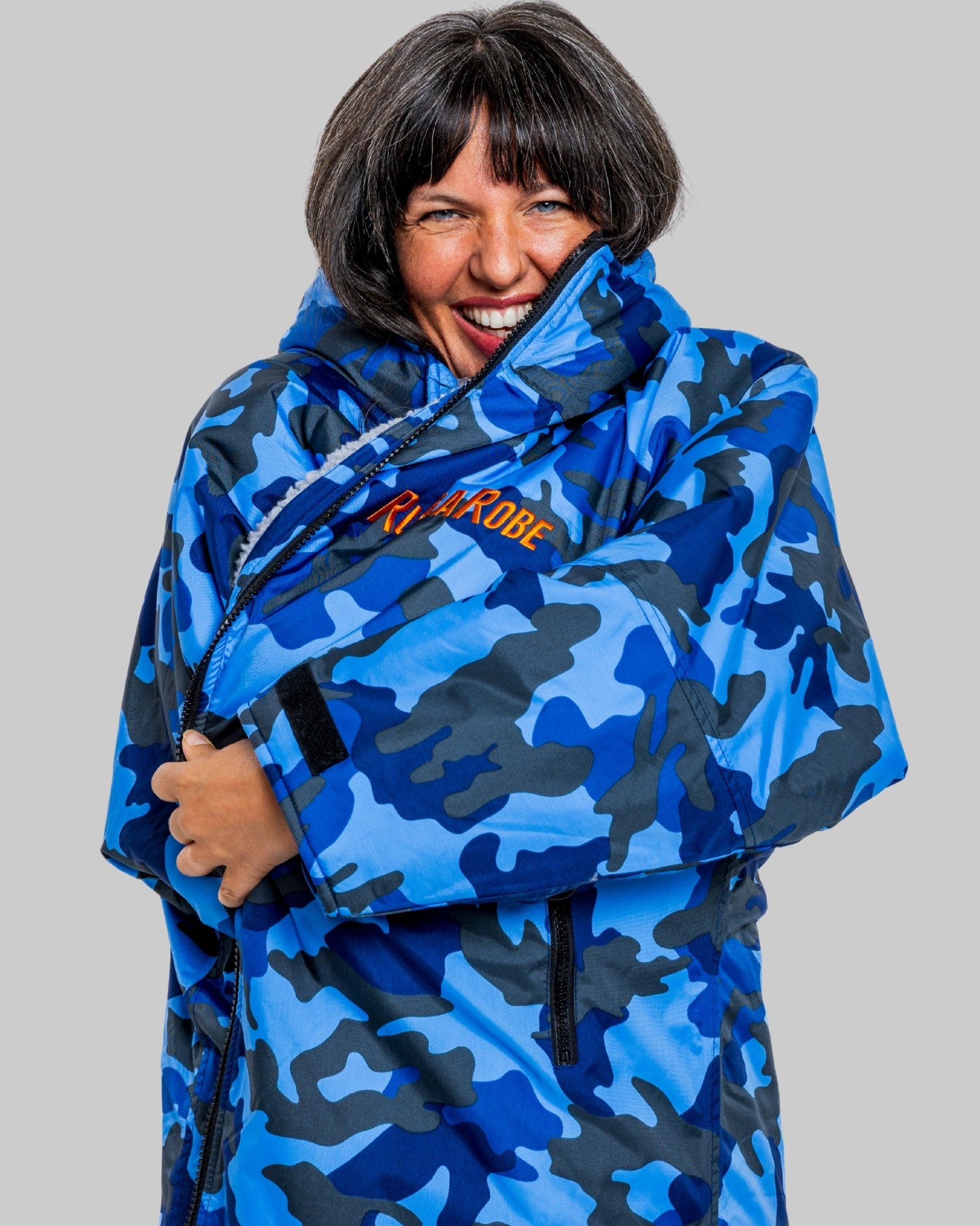 Person wearing a blue camouflage changerobe with a visible brand logo on a grey background