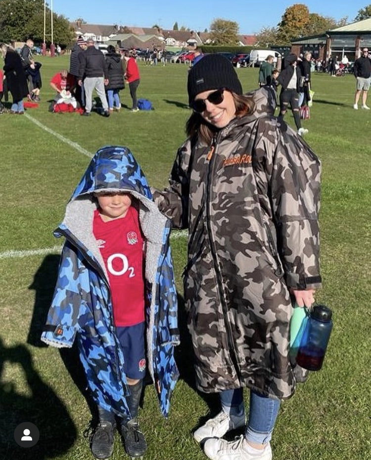 Two people wearing camoflage ruggarobes in a sportsfield