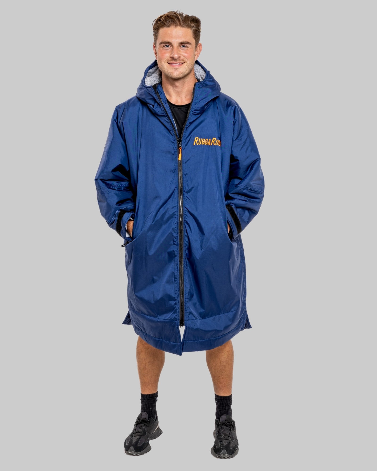 Man wearing a blue with grey fleece interior changerobe with visible brand logo on a grey background