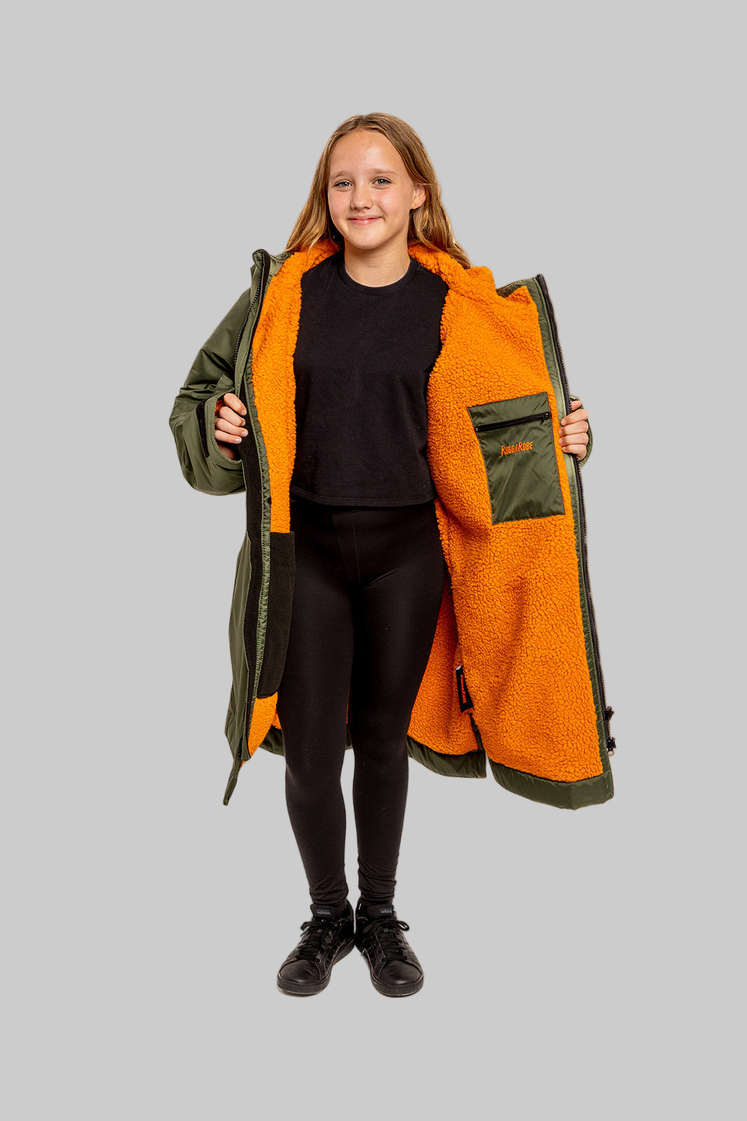 Model wearing RuggaRobe green change robe with orange fleece interior on grey background