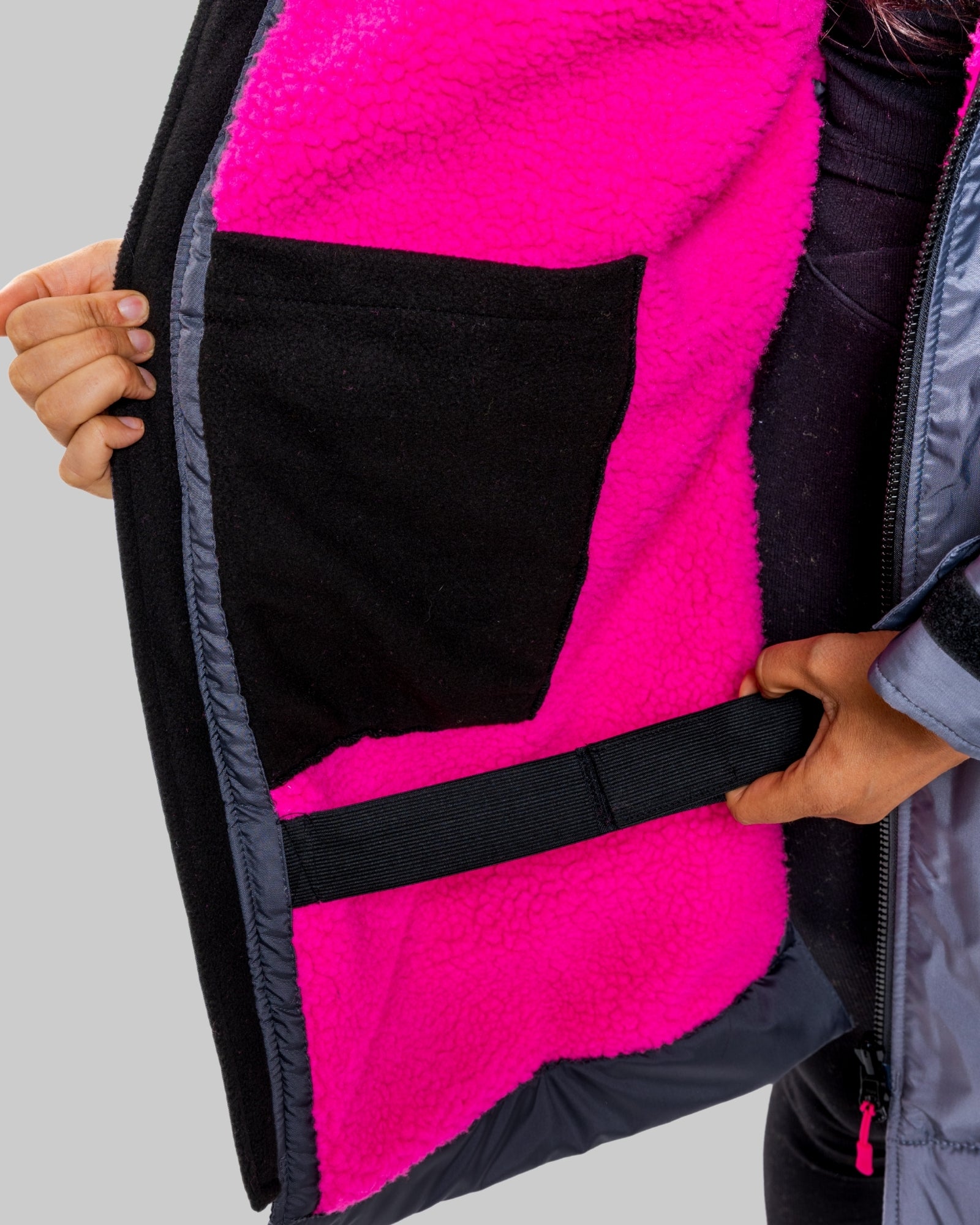 Model wearing a RuggaRobe slate grey change robe with pink fleece interior on a grey background, holding it open to reveal the interior.