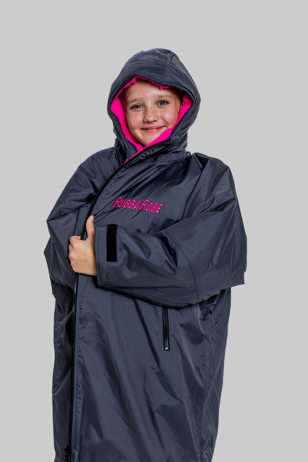 Child wearing a RuggaRobe slate grey change robe with pink fleece interior on a grey background