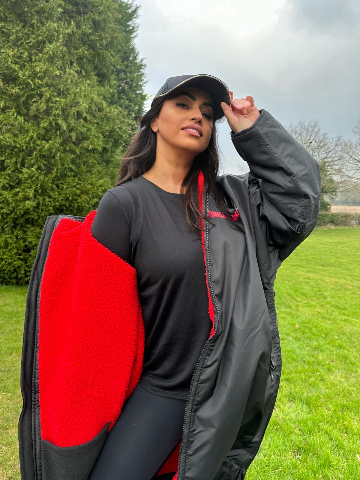 Model wearing RuggaRobe black change robe with red fleece interior in a sportsfield