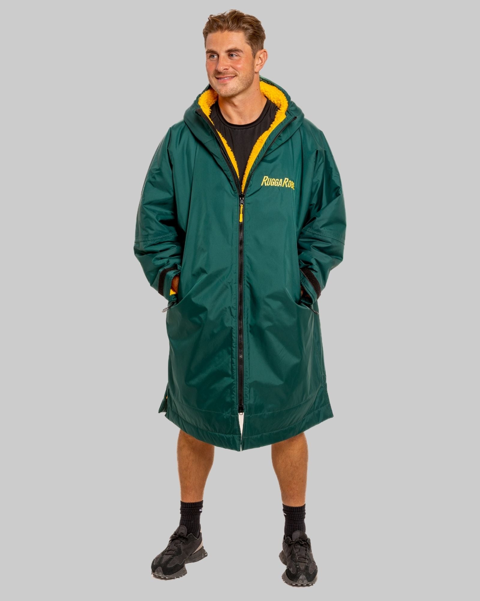 Person wearing a green with gold fleece change robe on a grey background