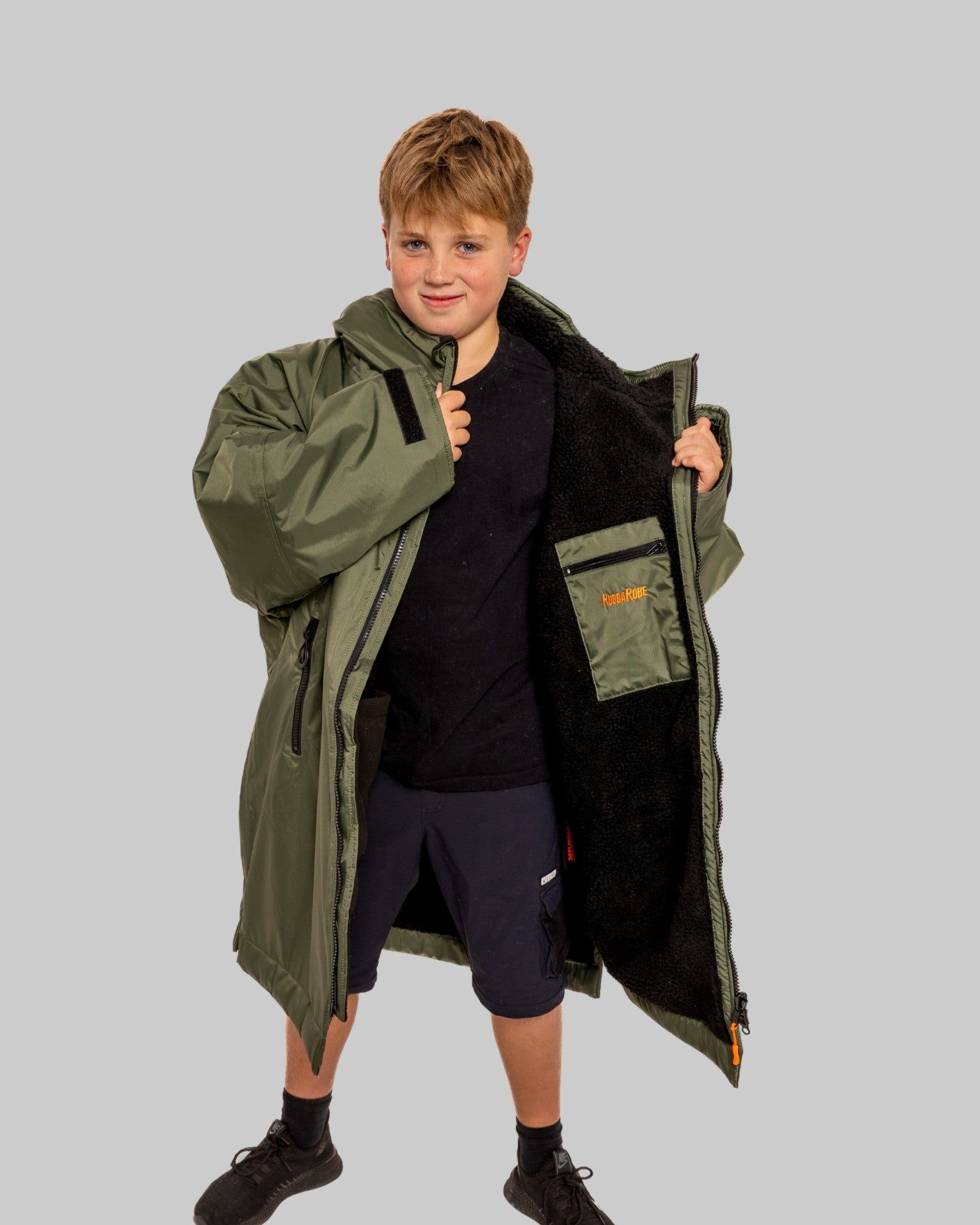 Model wearing RuggaRobe green change robe with black fleece interior on grey background