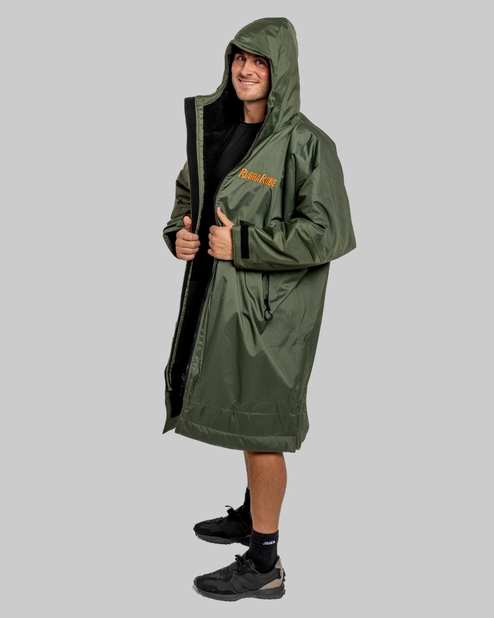Person wearing a green raincoat with a brand logo on a gray background