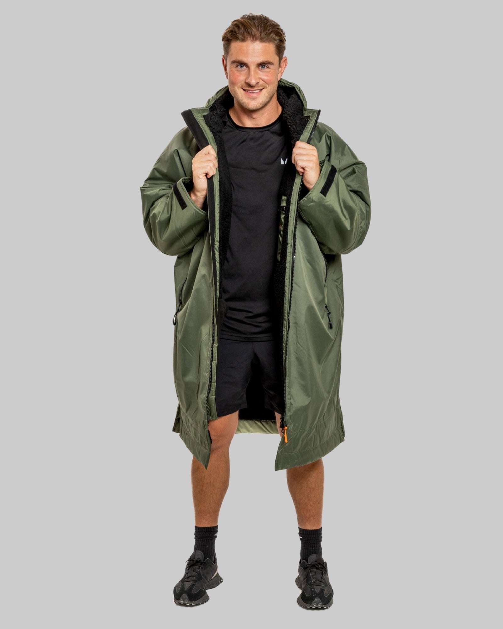 Man wearing a green change robe with black fleece with a brand logo on a grey background