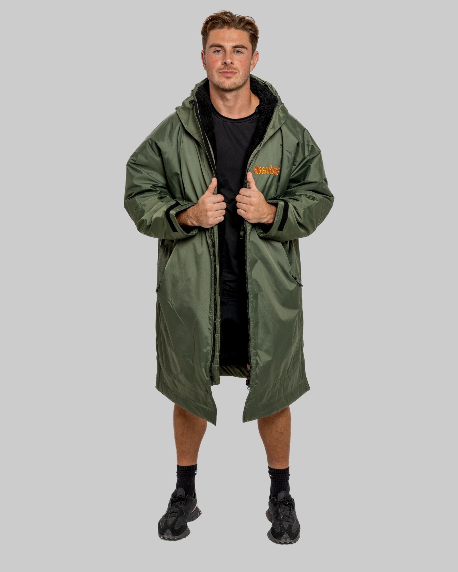 Man wearing a green change robe with black fleece with a brand logo on a grey background