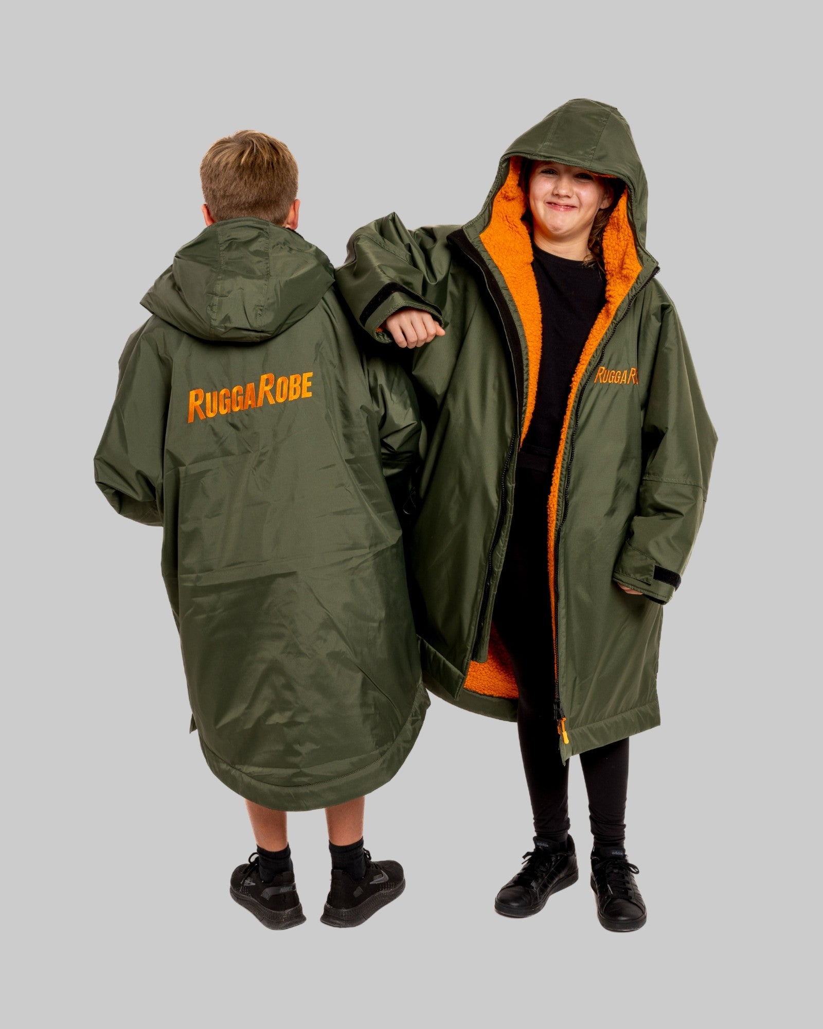 Two people wearing green hooded ruggarobes with orange interior, one  has 'RugraRobe' branding.