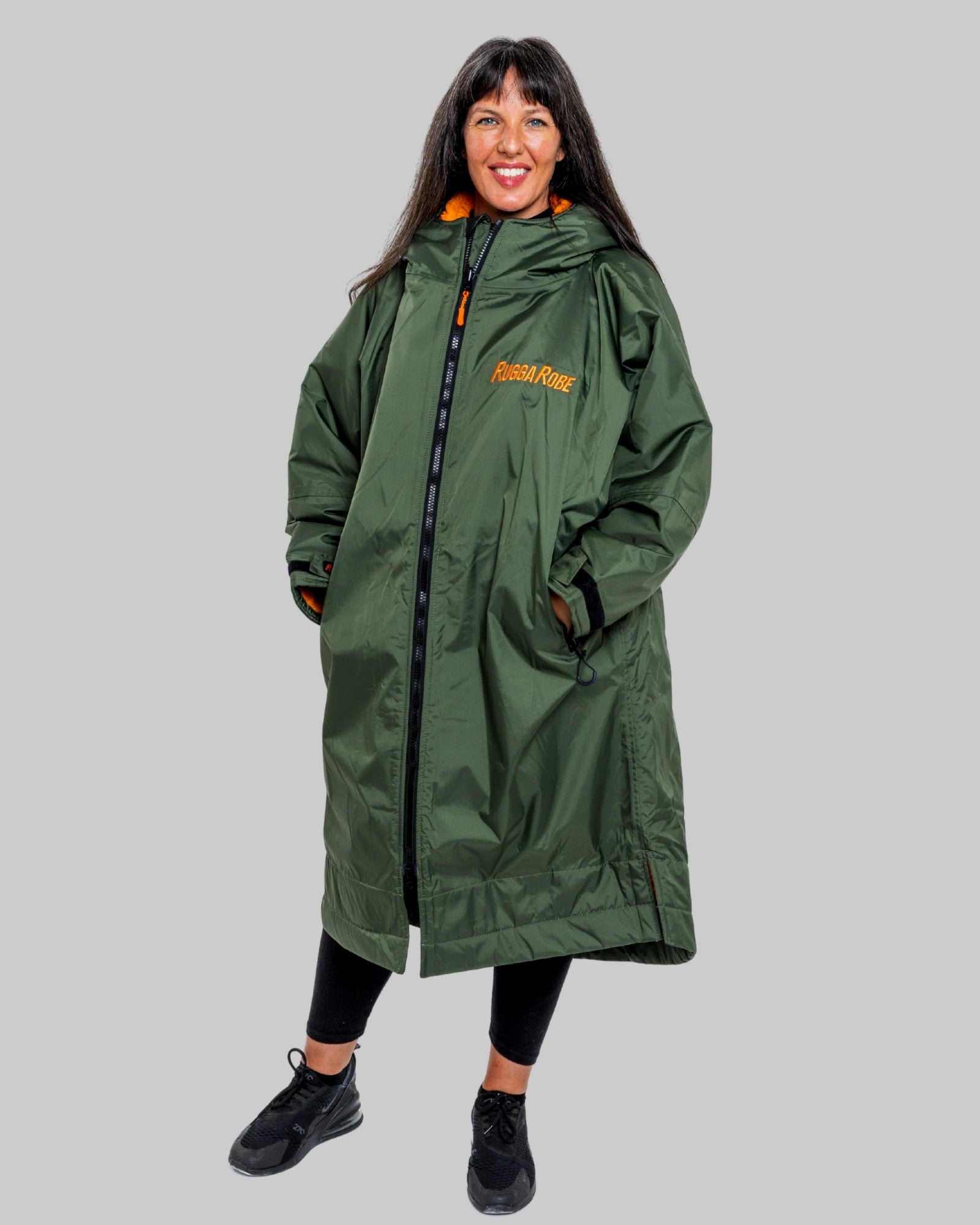 Person wearing a green ruggarobe with orange interior on a grey background