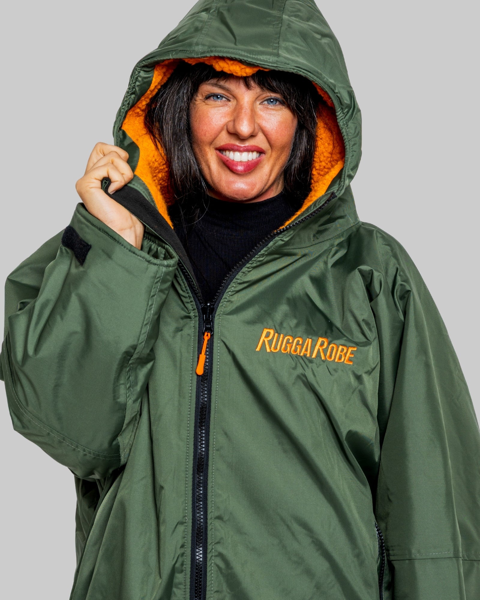 Person wearing a green raincoat with orange lining and 'Rugga Robe' branding on a gray background