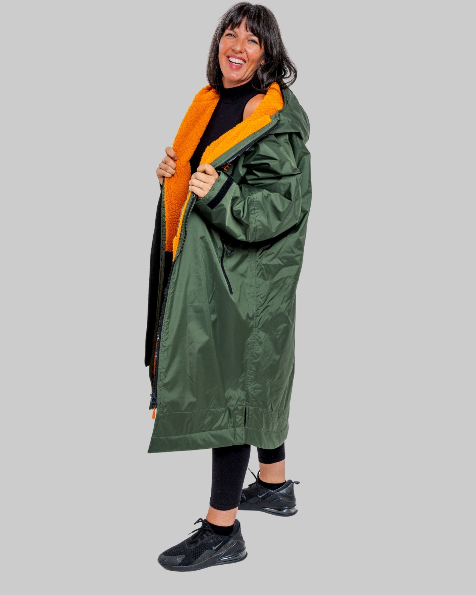 Person wearing a green ruggarobe with orange interior on a grey background