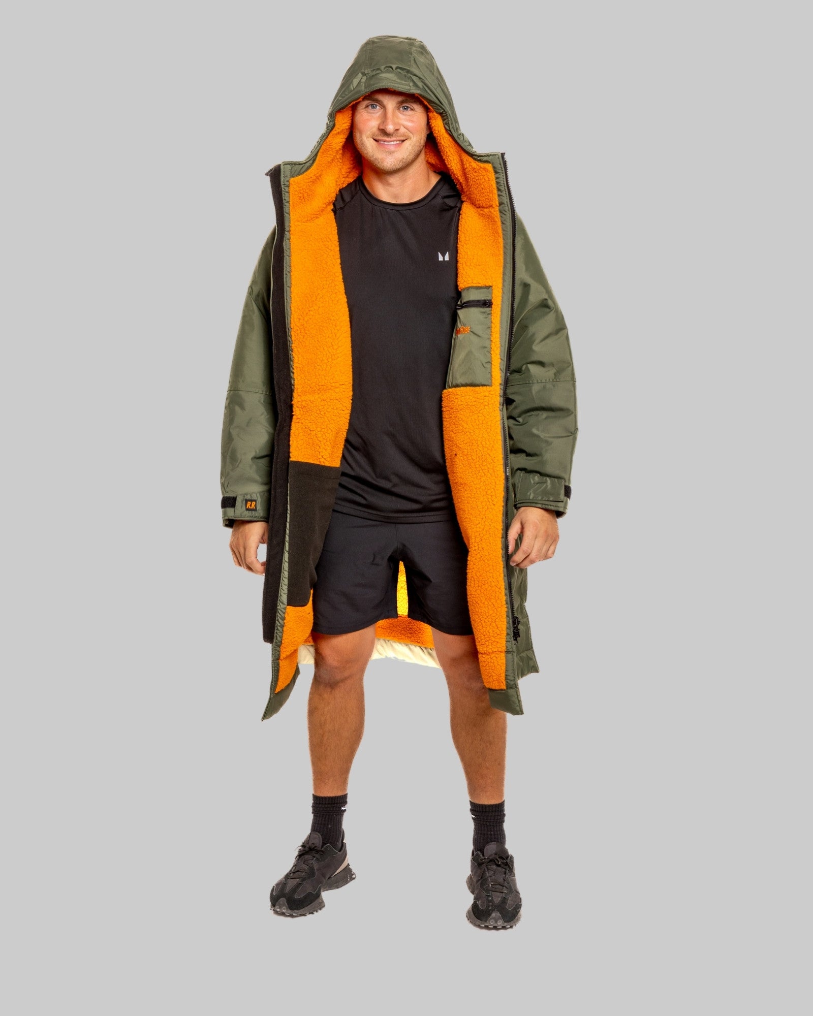 Person wearing a green ruggarobe with orange interior on a grey background
