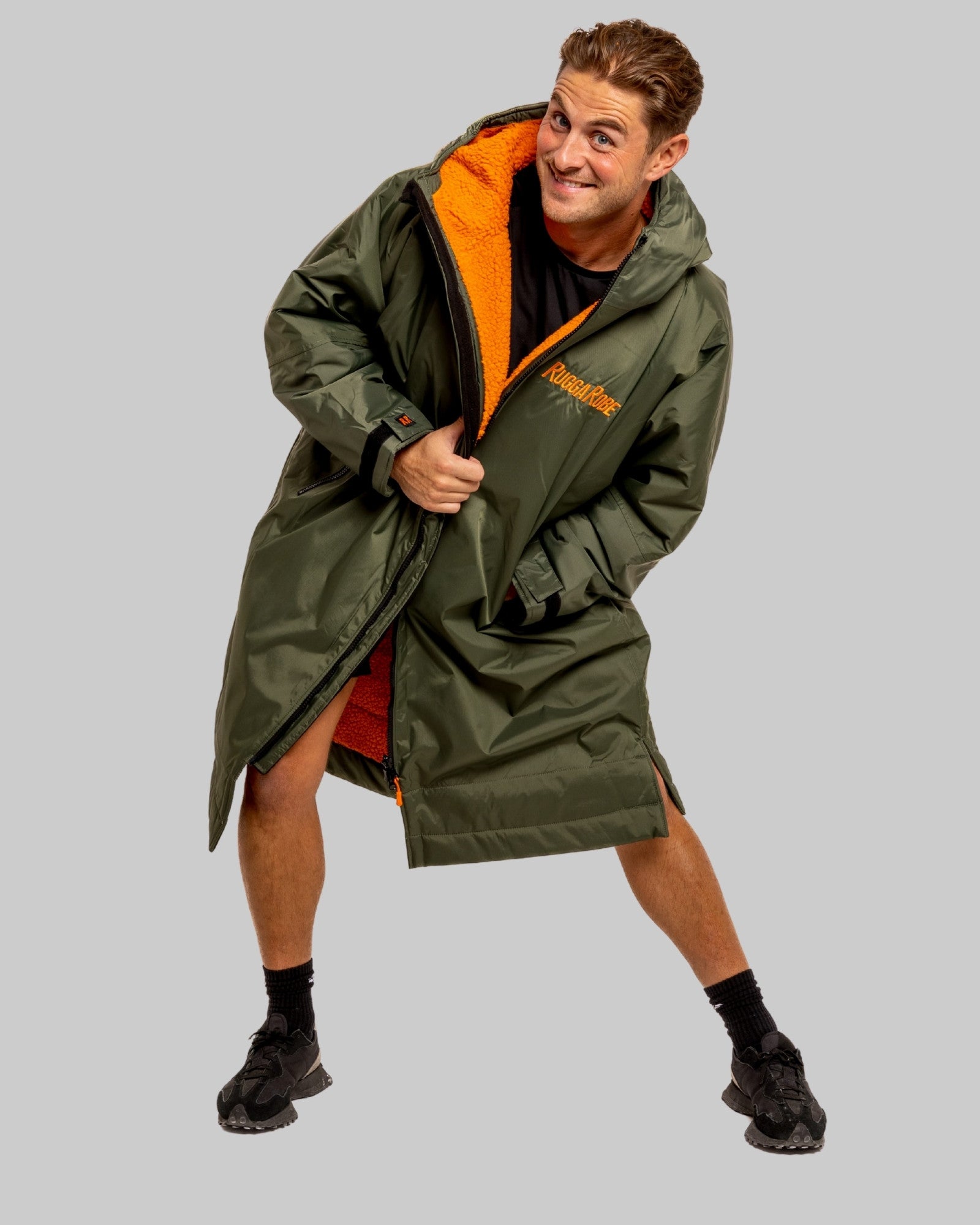 Person wearing a green ruggarobe with orange interior on a grey background