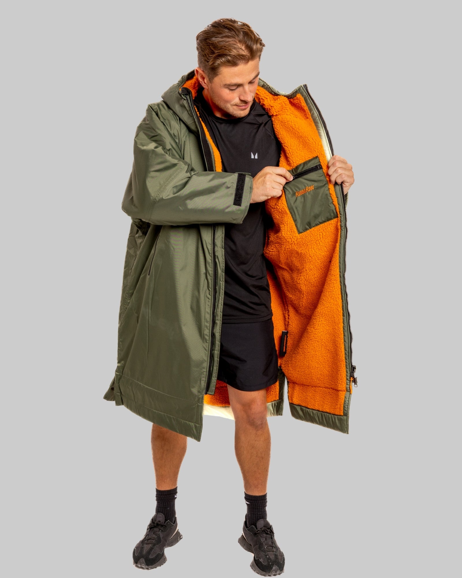 Man wearing a green and orange ruggarobe on a grey background