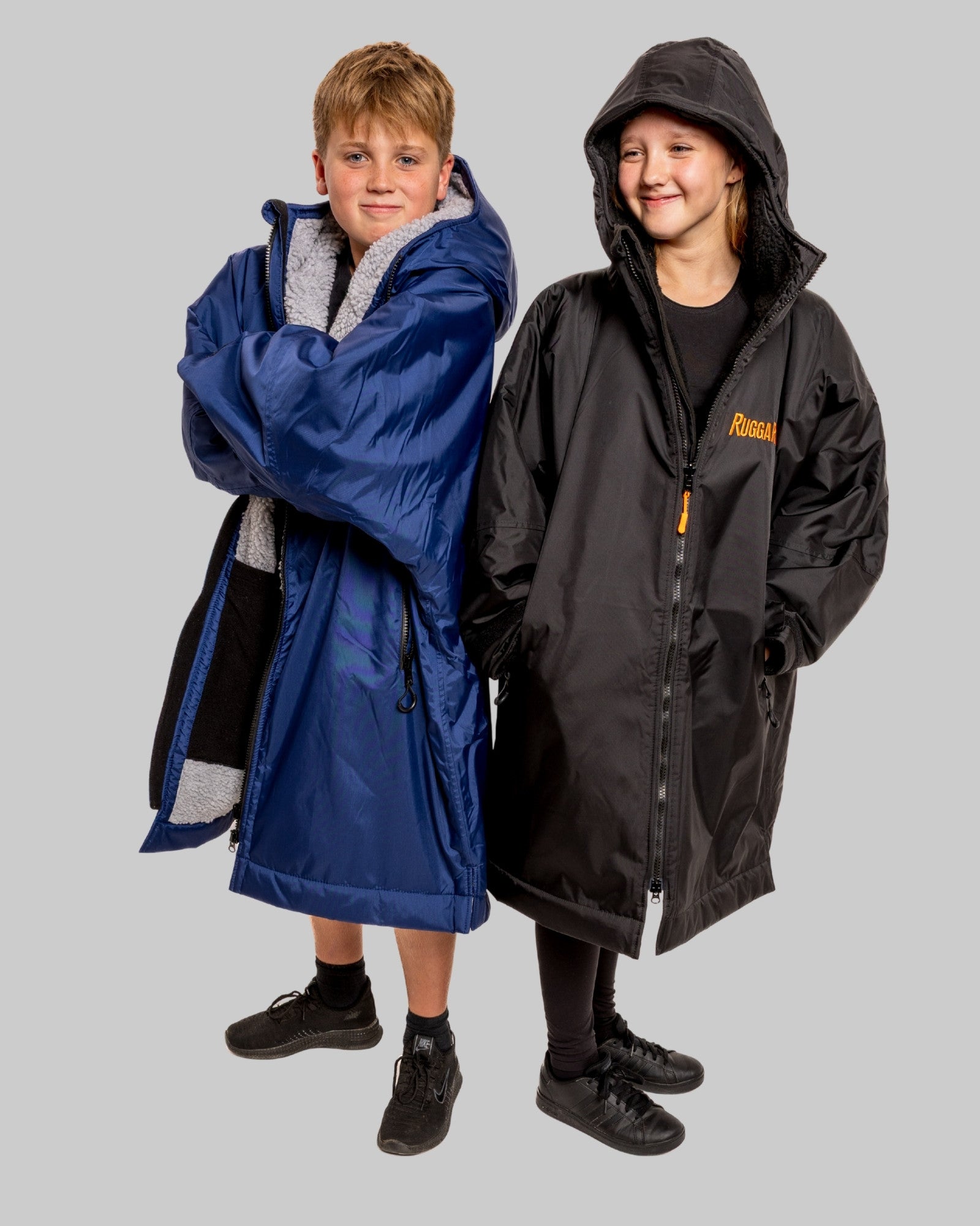 2 Children wearing RugaRobe change robes, one blue robe and one black robe on a grey background